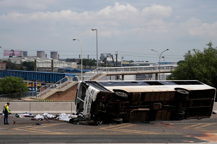 A forensic officer investigate a bus that overturned on a highway in Johannesburg, South Africa, Tuesday, March 11, 2025, killing multiple people and injuring some. (AP Photo/Alfonso Nqunjana)