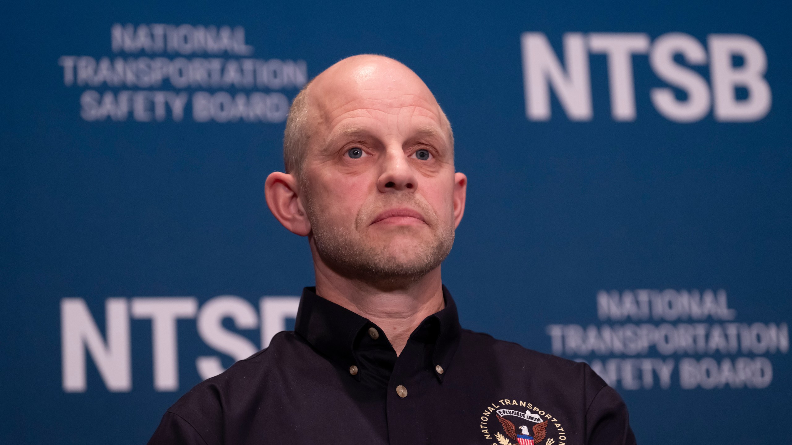 Investigator in charge Brice Banning listens as National Transportation Safety Board (NTSB) Chairwoman Jennifer Homendy speaks about the recent mid-air collision of an American Airlines flight and a Black Hawk helicopter near Ronald Reagan Washington National Airport, at a news conference in Washington, Tuesday, March 11, 2025. (AP Photo/Ben Curtis)