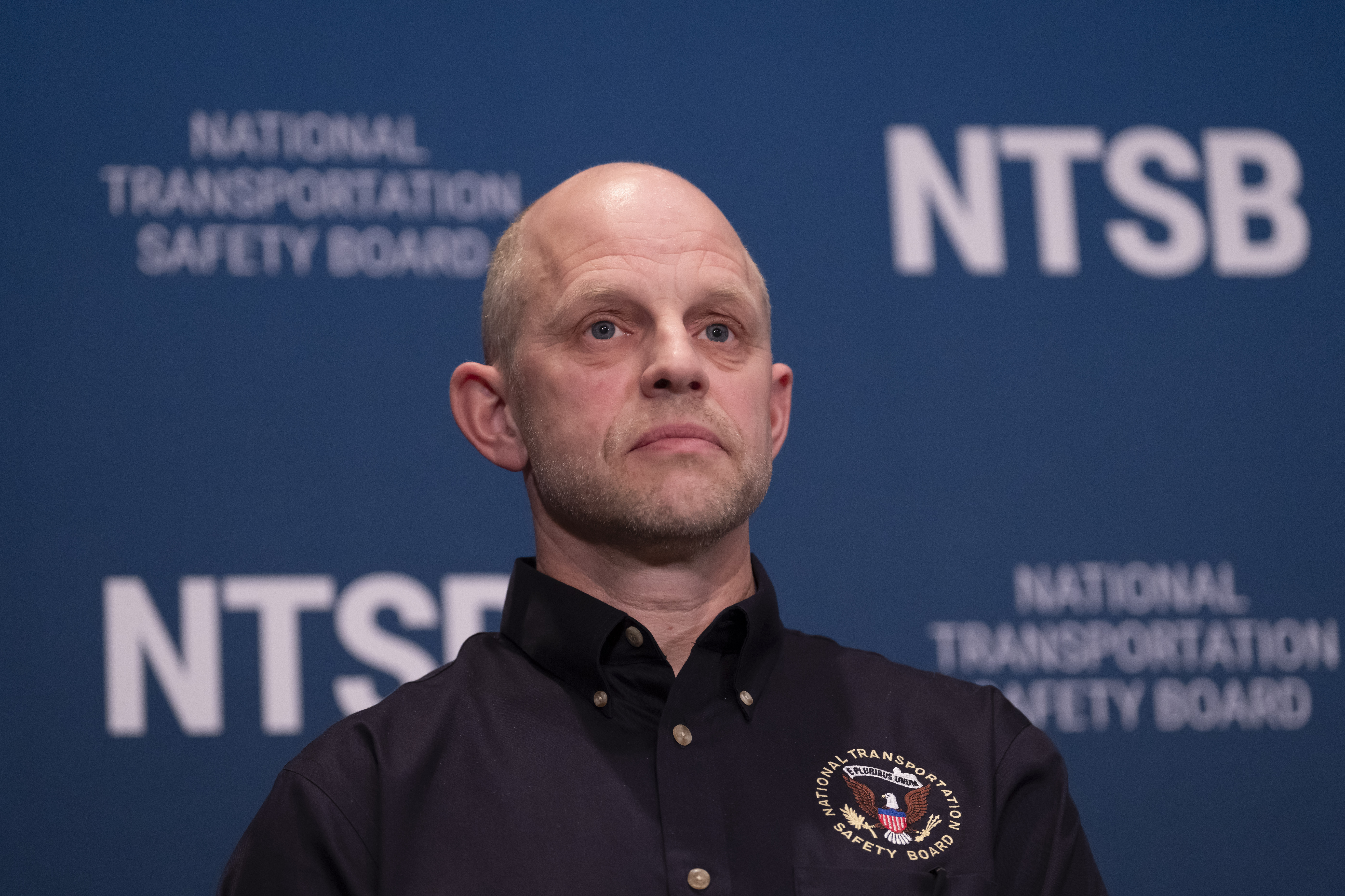 Investigator in charge Brice Banning listens as National Transportation Safety Board (NTSB) Chairwoman Jennifer Homendy speaks about the recent mid-air collision of an American Airlines flight and a Black Hawk helicopter near Ronald Reagan Washington National Airport, at a news conference in Washington, Tuesday, March 11, 2025. (AP Photo/Ben Curtis)