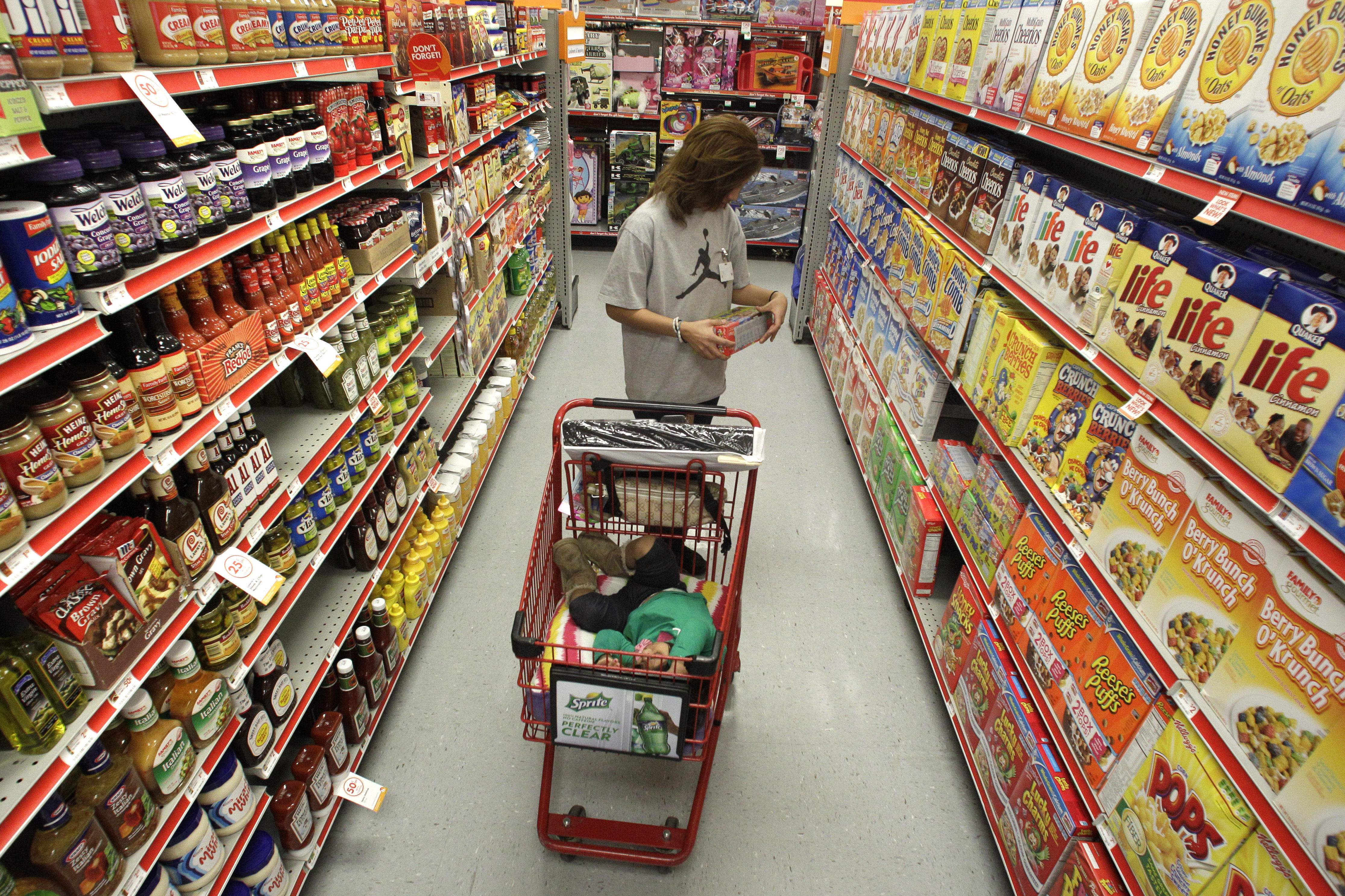 FILE - A woman looks at products in the aisle of a store as her daughter naps in the shopping cart in Waco, Texas, on Dec. 14, 2010. (AP Photo/Tony Gutierrez, File)