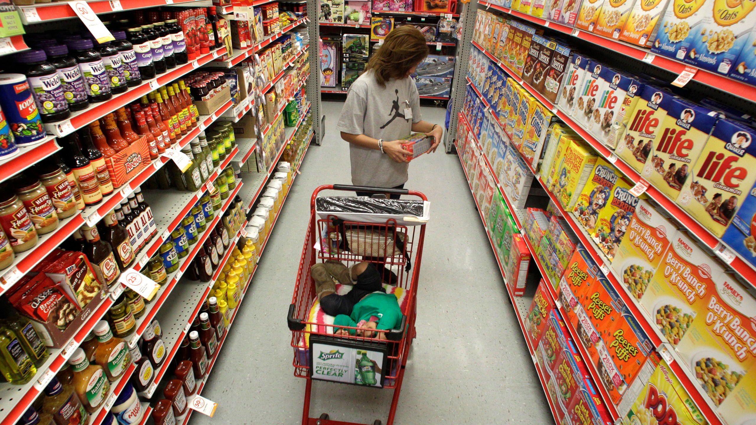 FILE - A woman looks at products in the aisle of a store as her daughter naps in the shopping cart in Waco, Texas, on Dec. 14, 2010. (AP Photo/Tony Gutierrez, File)