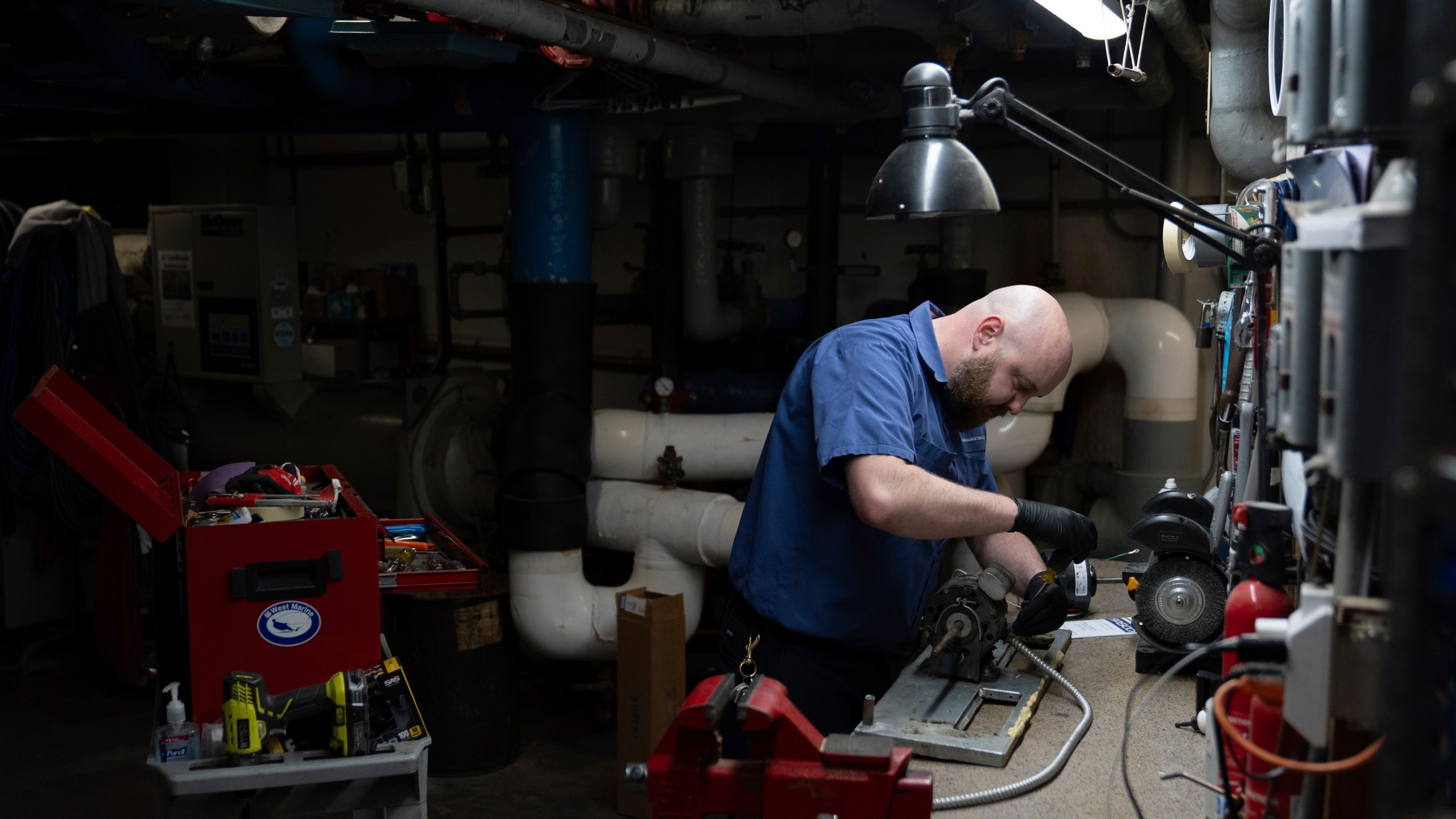 James Richardson works on a heating and cooling unit in the broiler room at Smith Tower Apartments in Vancouver, Wash., on Monday, March 10, 2025. (AP Photo/Jenny Kane)