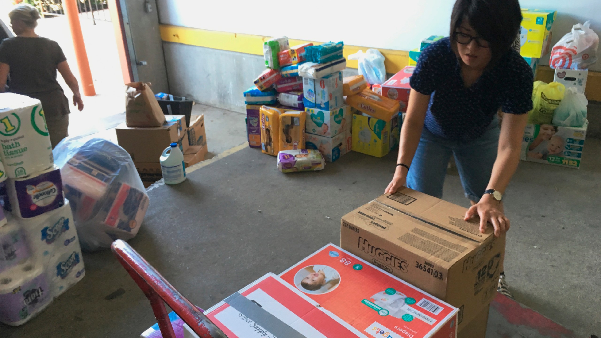 FILE - Catholic Charities of the Rio Grande Valley volunteer Veronica Yoo loads boxes of donations on to a cart at a storage facility in McAllen, Texas on June 24, 2018. (AP Photo/Manuel Valdes, File)