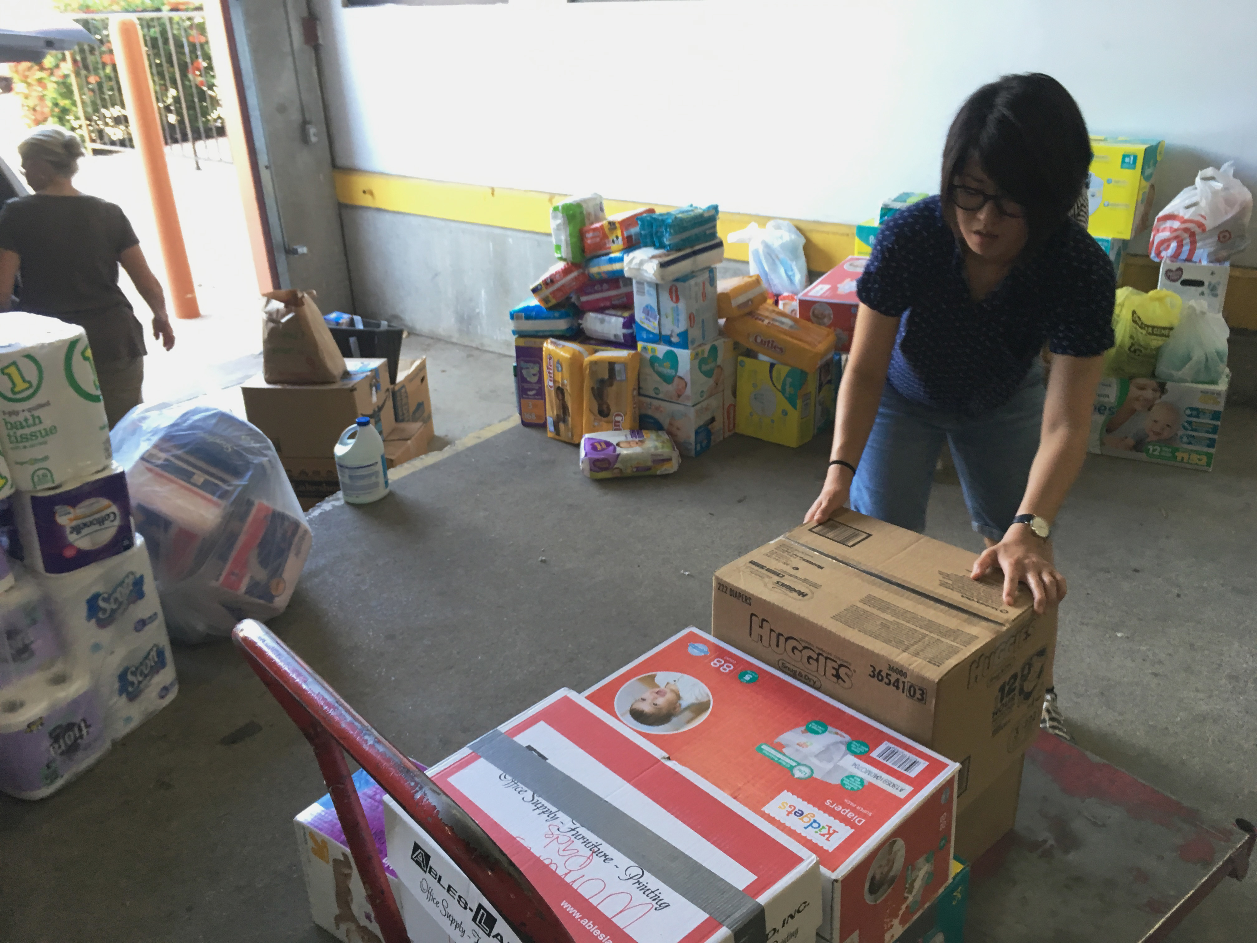 FILE - Catholic Charities of the Rio Grande Valley volunteer Veronica Yoo loads boxes of donations on to a cart at a storage facility in McAllen, Texas on June 24, 2018. (AP Photo/Manuel Valdes, File)