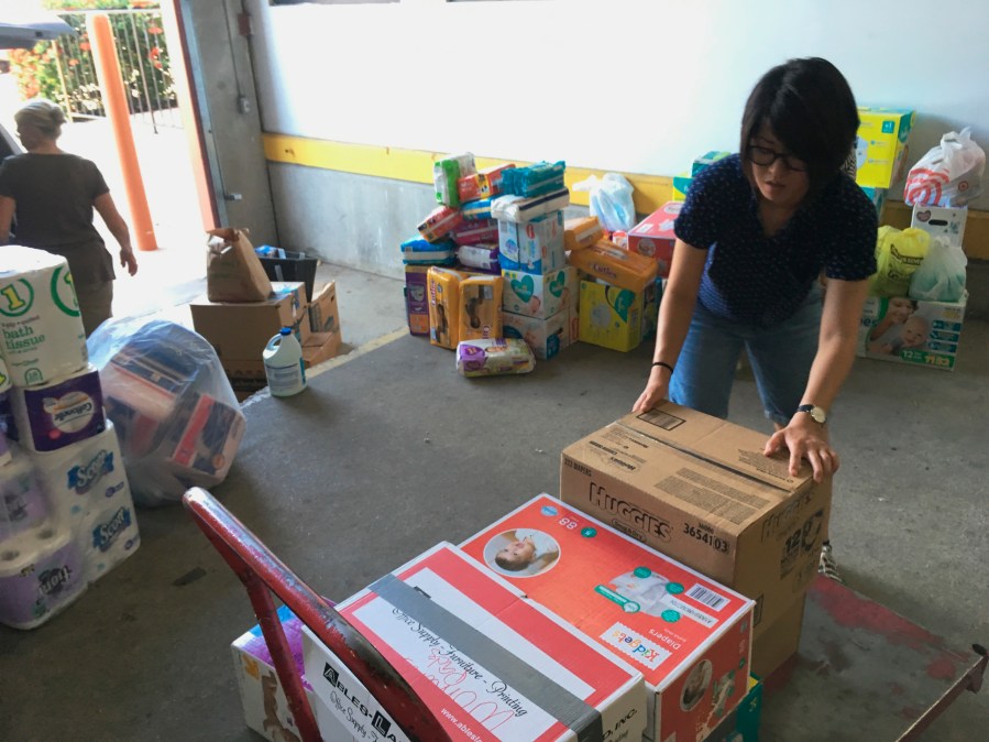 FILE - Catholic Charities of the Rio Grande Valley volunteer Veronica Yoo loads boxes of donations on to a cart at a storage facility in McAllen, Texas on June 24, 2018. (AP Photo/Manuel Valdes, File)