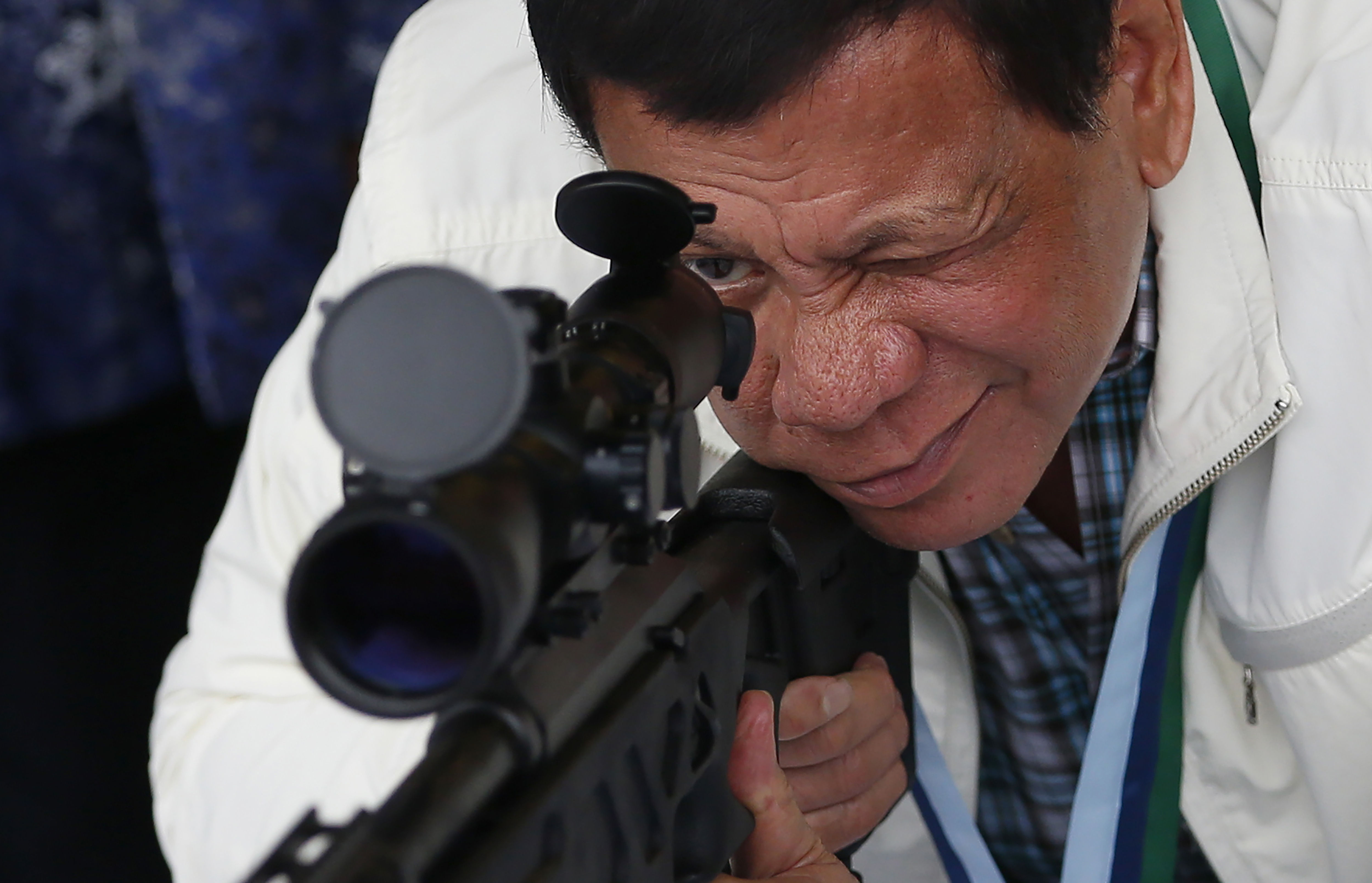 FILE - Philippine President Rodrigo Duterte checks the scope of a Chinese-made CS/LR4A sniper rifle during the presentation of thousands of rifles and ammunition by China to the Philippines at Clark Airbase in northern Philippines on June 28, 2017. (AP Photo/Bullit Marquez, File)