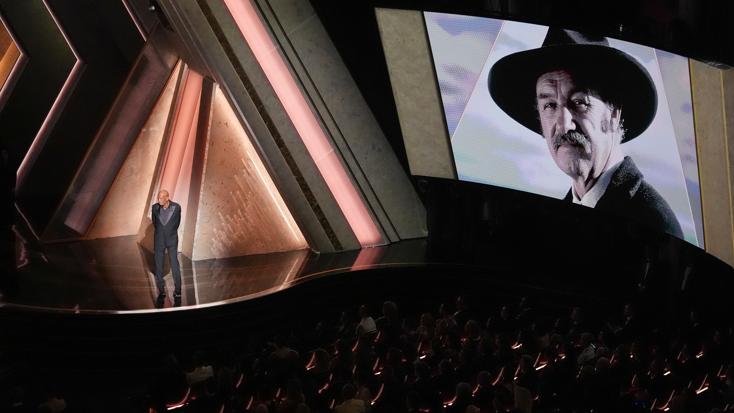 Morgan Freeman speaks about Gene Hackman with an image of Gene Hackman on the screen during the Oscars on Sunday, March 2, 2025, at the Dolby Theatre in Los Angeles. (AP Photo/Chris Pizzello)