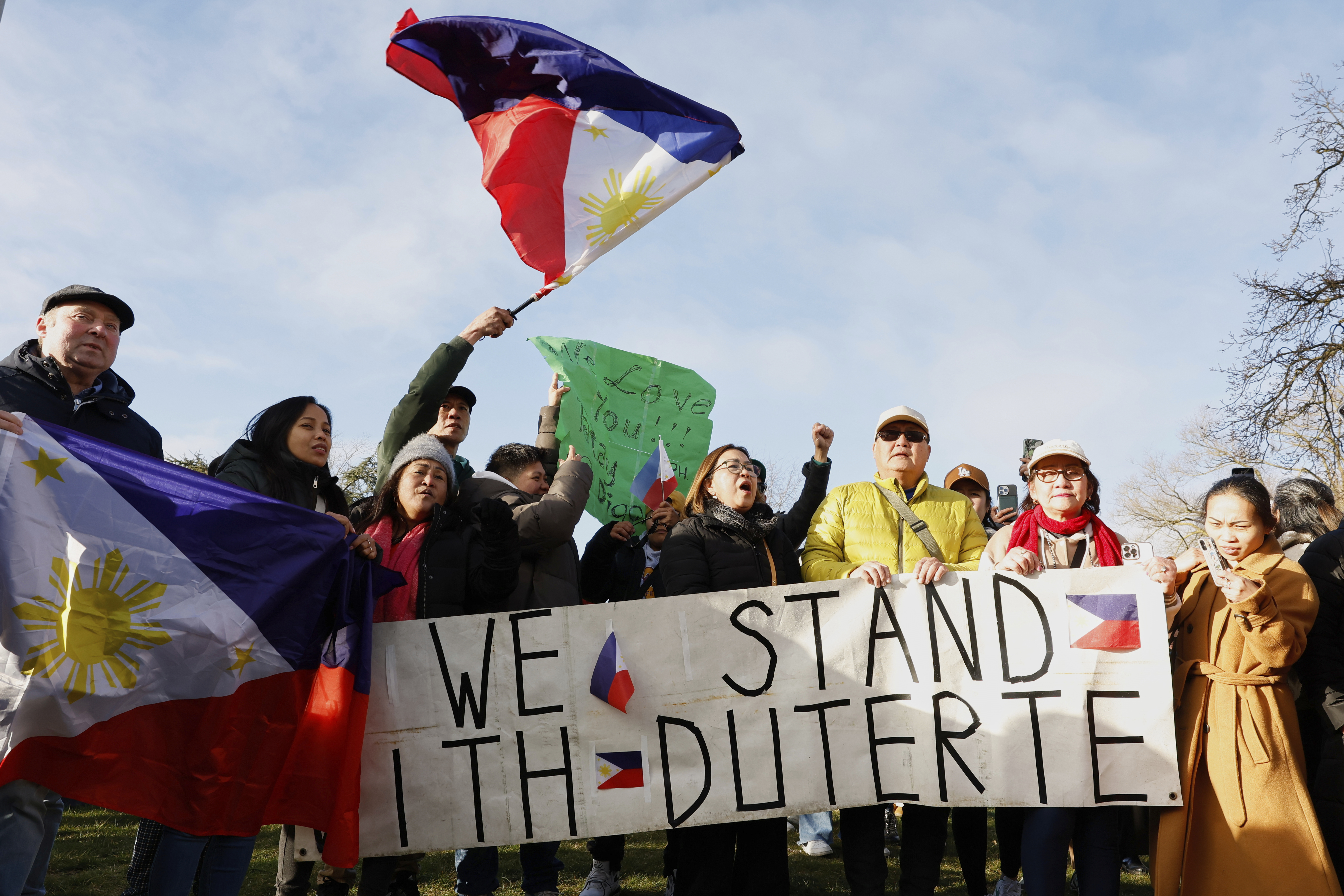 Supporters of former Philippine President Rodrigo Duterte wave a flag and banner during a demonstration outside the International Criminal Court detention center near The Hague in Scheveningen, Netherlands, Wednesday, March 12, 2025. (AP Photo/Omar Havana)