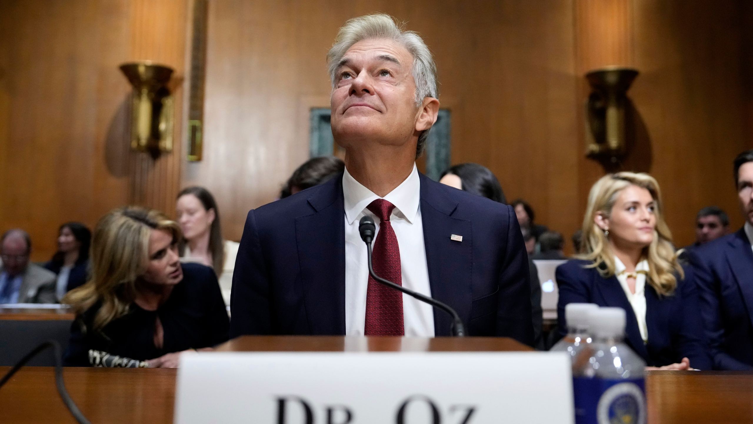 Dr. Mehmet Oz, President Donald Trump's pick to lead the Centers for Medicare and Medicaid Services, joined by wife Lisa Oz, left, and daughter Daphne Oz, right, sits before testifying at his confirmation hearing before the Senate Finance Committee, on Capitol Hill in Washington, Friday, March 14, 2025. (AP Photo/Ben Curtis)