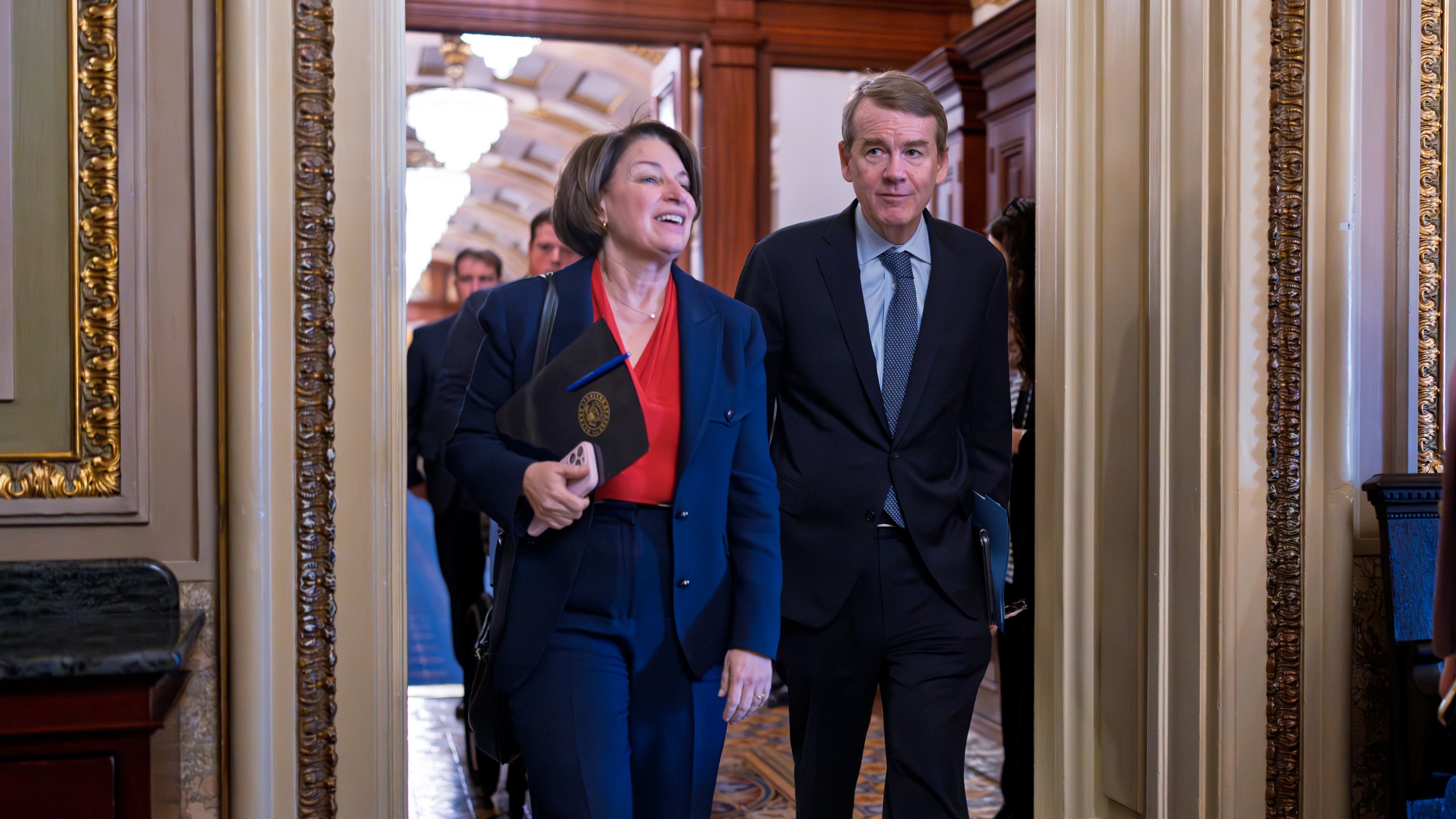 Sen. Amy Klobuchar, D-Minn.,, left, and Sen. Michael Bennet, D-Colo., arrive as Senate Democrats gather behind closed doors to mount a last-ditch protest over a Republican-led spending bill that already passed the House, at the Capitol in Washington, Thursday, March 13, 2025. (AP Photo/J. Scott Applewhite)