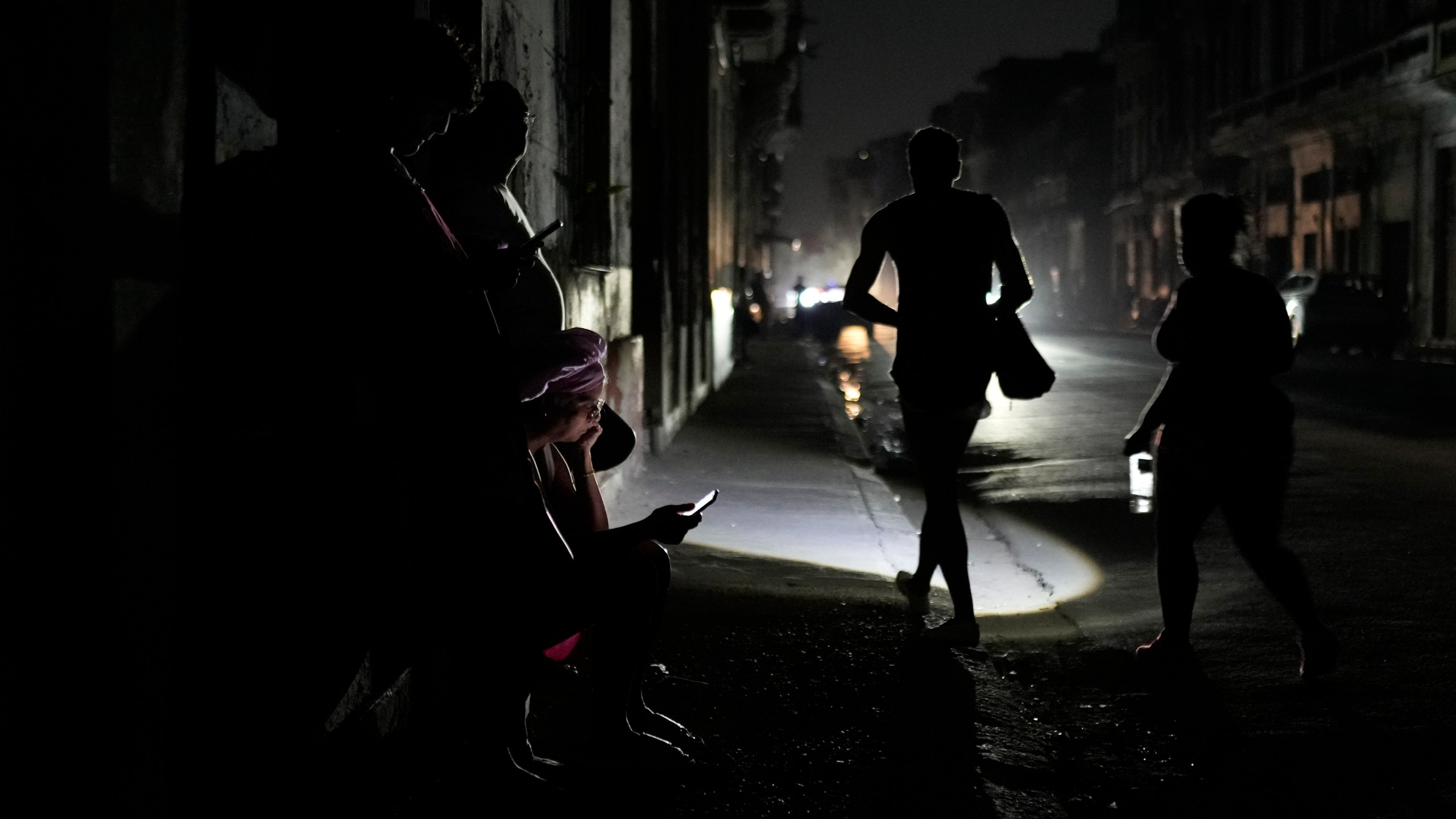 Residents walk on a street during a general blackout in Havana, Cuba, Friday, March 14, 2025. (AP Photo/Ramon Espinosa)