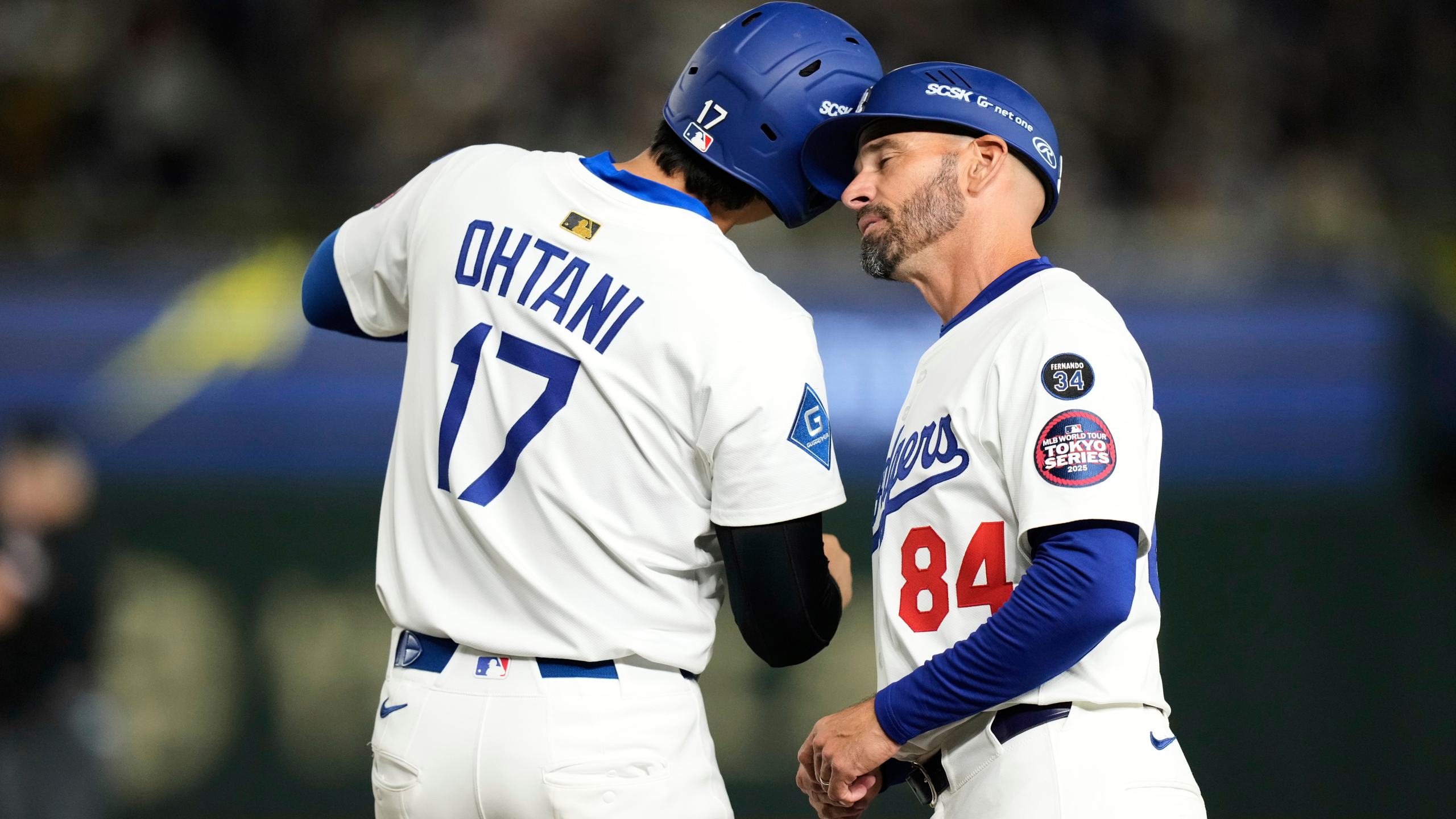 Los Angeles Dodgers' Shohei Ohtani, left, and first base coach Chris Woodward, right, greet each other after Ohtani earned a walk in the first inning of a spring training baseball game against the Yomiuri Giants in Tokyo, Japan, Saturday, March 15, 2025. (AP Photo/Hiro Komae)