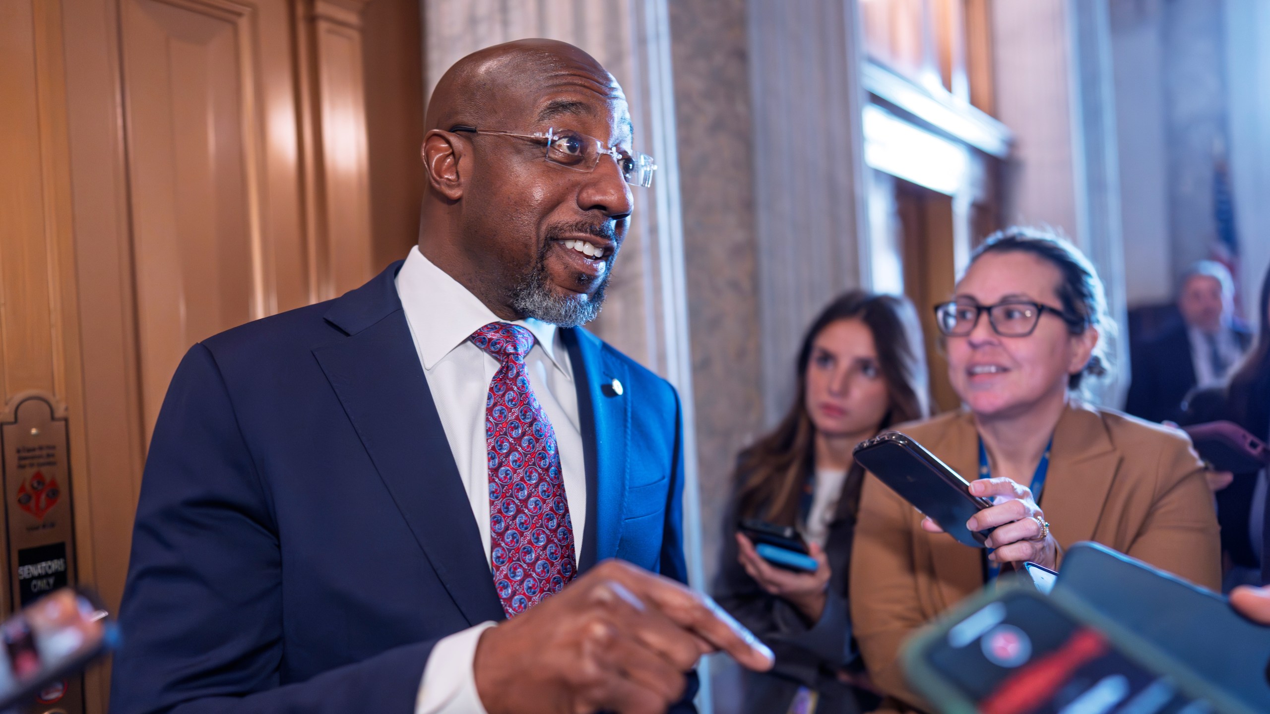 Sen. Raphael Warnock, D-Ga., responds to reporters as the Senate works to avert a partial government shutdown ahead of the midnight deadline, at the Capitol in Washington, Friday, March 14, 2025. (AP Photo/J. Scott Applewhite)