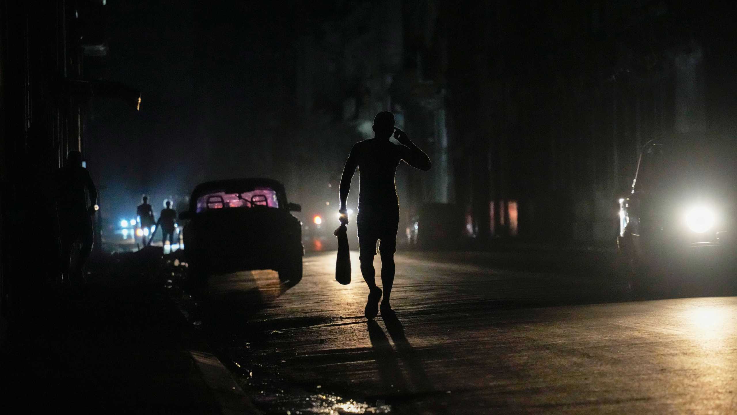 A resident walks on a street during a general blackout in Havana, Cuba, Friday, March 14, 2025. (AP Photo/Ramon Espinosa)