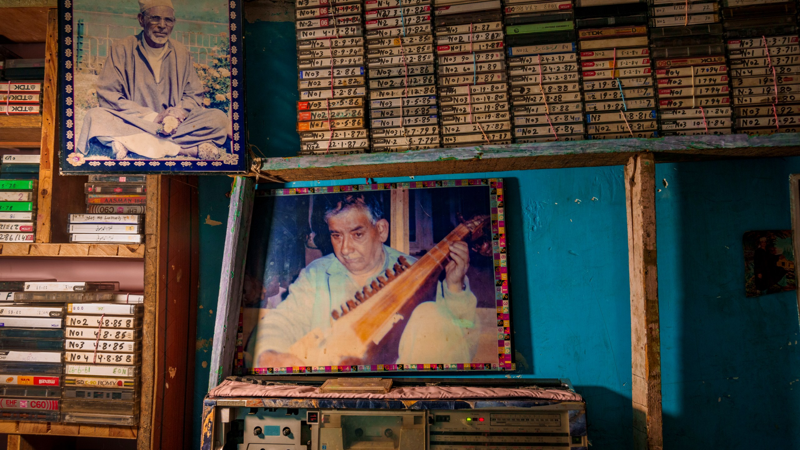 Photographs of Sufi saint Mohammad Rajab Shaksaz, left, and the late Sufi singer Ghulam Ahmad Sofi, center, along with a collection of his cassettes with his songs, are displayed inside a tailor shop owned by Farooq Ahmad Shaksaz in outskirts of Srinagar, Indian controlled Kashmir, Friday, Feb. 14, 2025. (AP Photo/Dar Yasin)