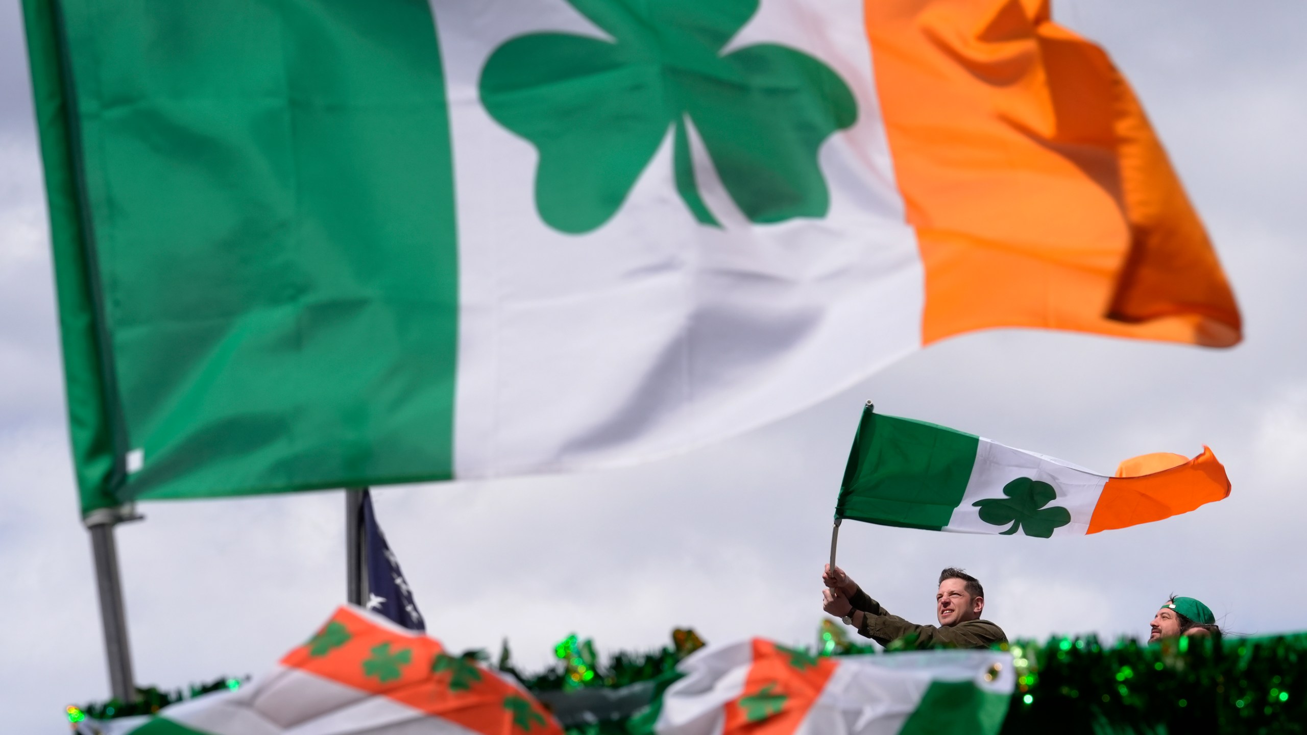 FILE - A person waves an Irish flag while watching the St. Patrick's Day parade, Sunday, March 17, 2024, in Boston's South Boston neighborhood. (AP Photo/Steven Senne, File)