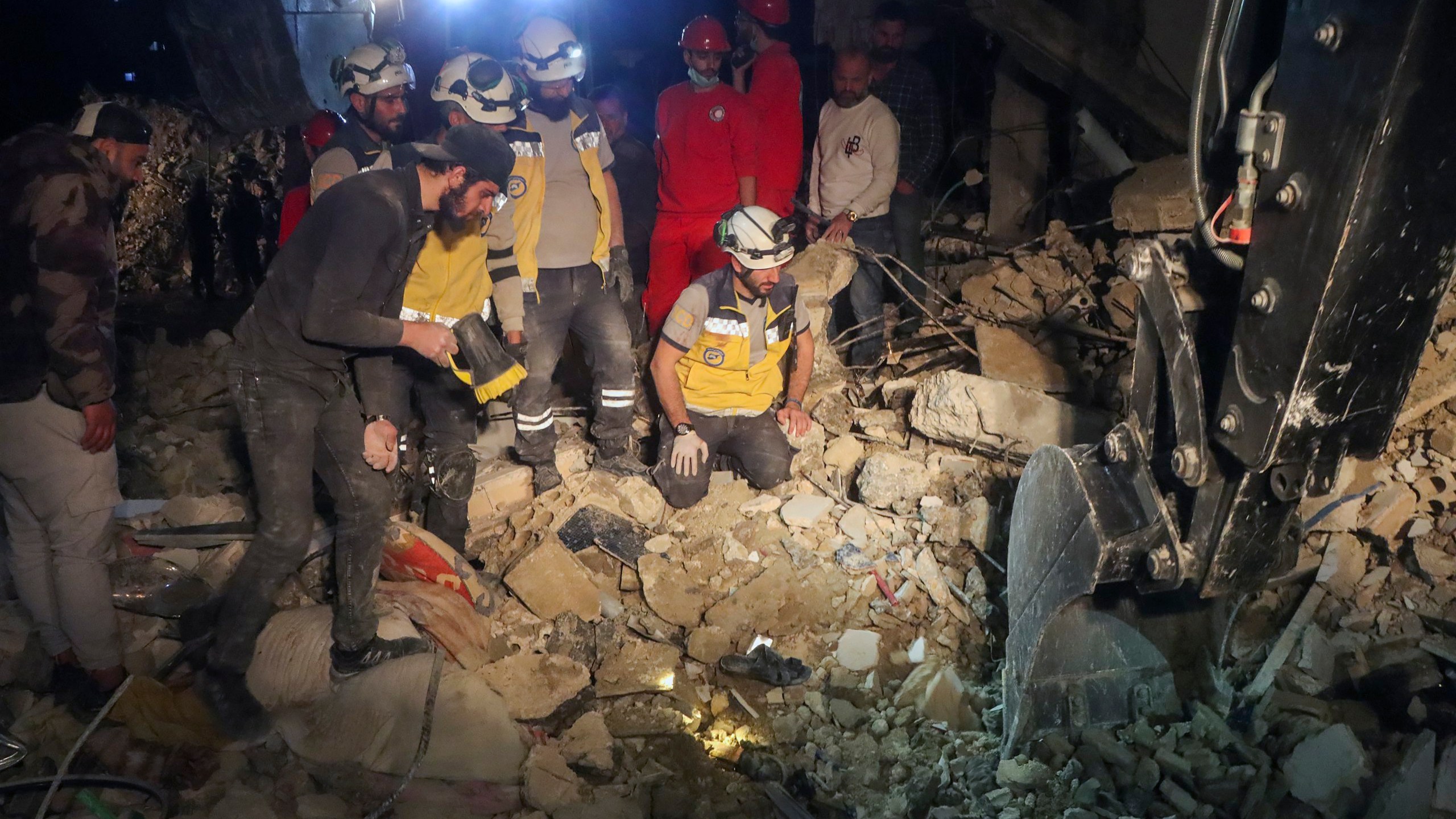 In this photo provided by the Syrian Civil Defense White Helmets, members of their team search through the debris of a four-story building after an ordnance from Syria's 13-conflict exploded in the coastal city of Latakia, Syria, early Sunday, March 16, 2025. 2025. The White Helmets said it worked overnight and recovered 16 bodies. (Syrian Civil Defense White Helmets via AP)