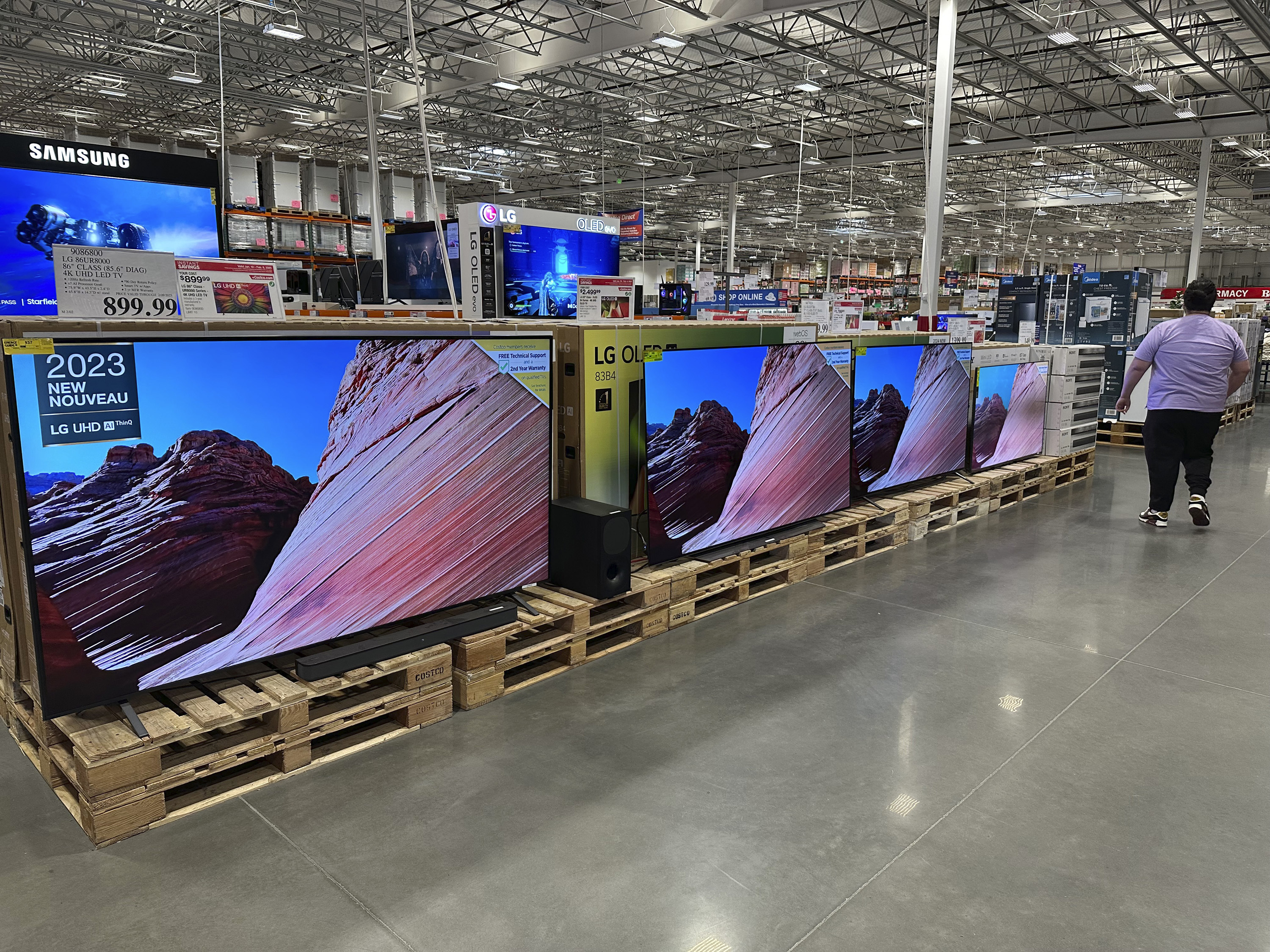 A shopper passes by a display of large-screen televisions in a Costco warehouse Monday, Feb. 3, 2025, in east Denver. (AP Photo/David Zalubowski)