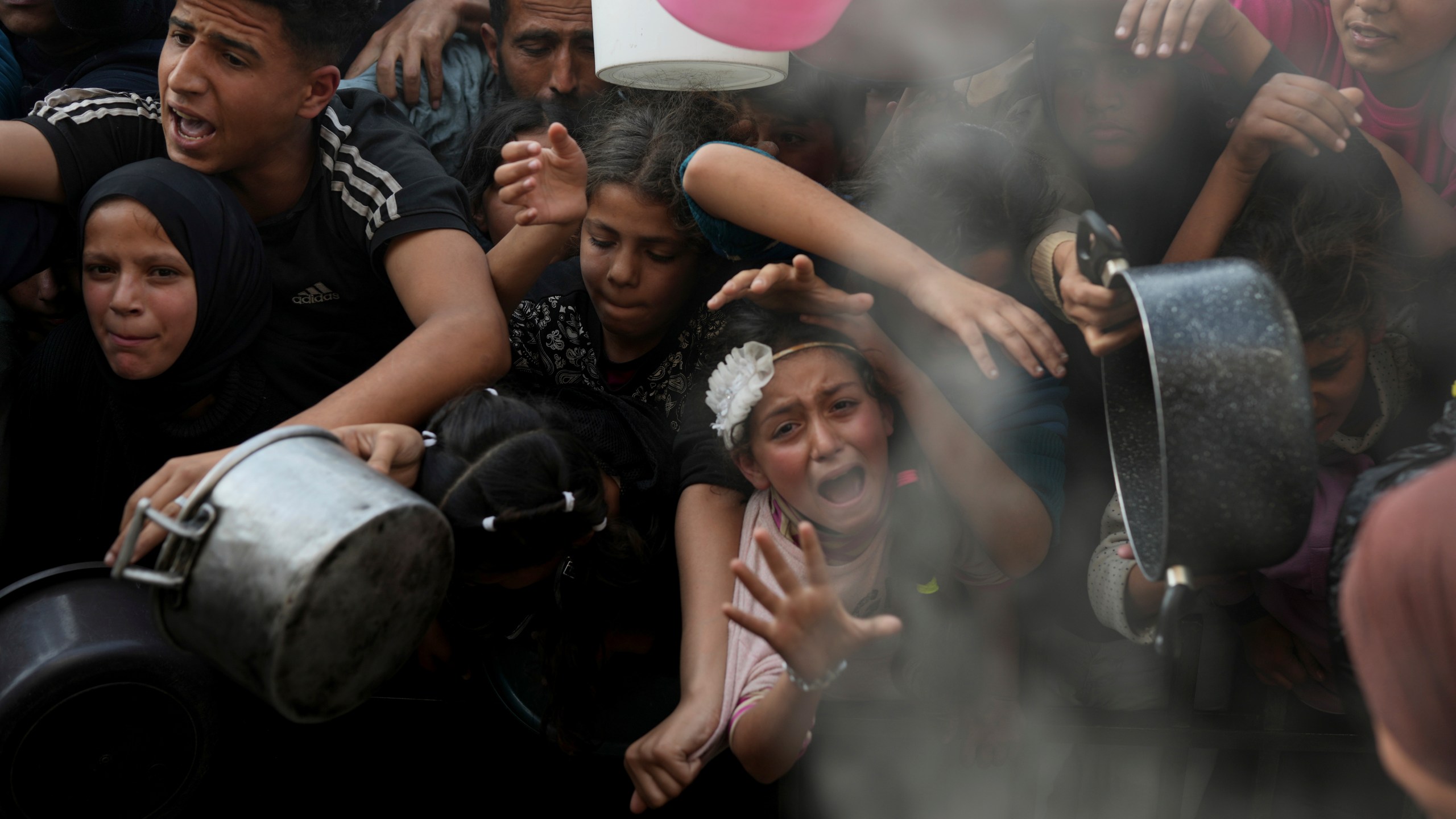 A Palestinian girl struggles as she and others try to get donated food at a distribution center in Beit Lahiya, northern Gaza Strip, Sunday, March 16, 2025. (AP Photo/Abdel Kareem Hana)