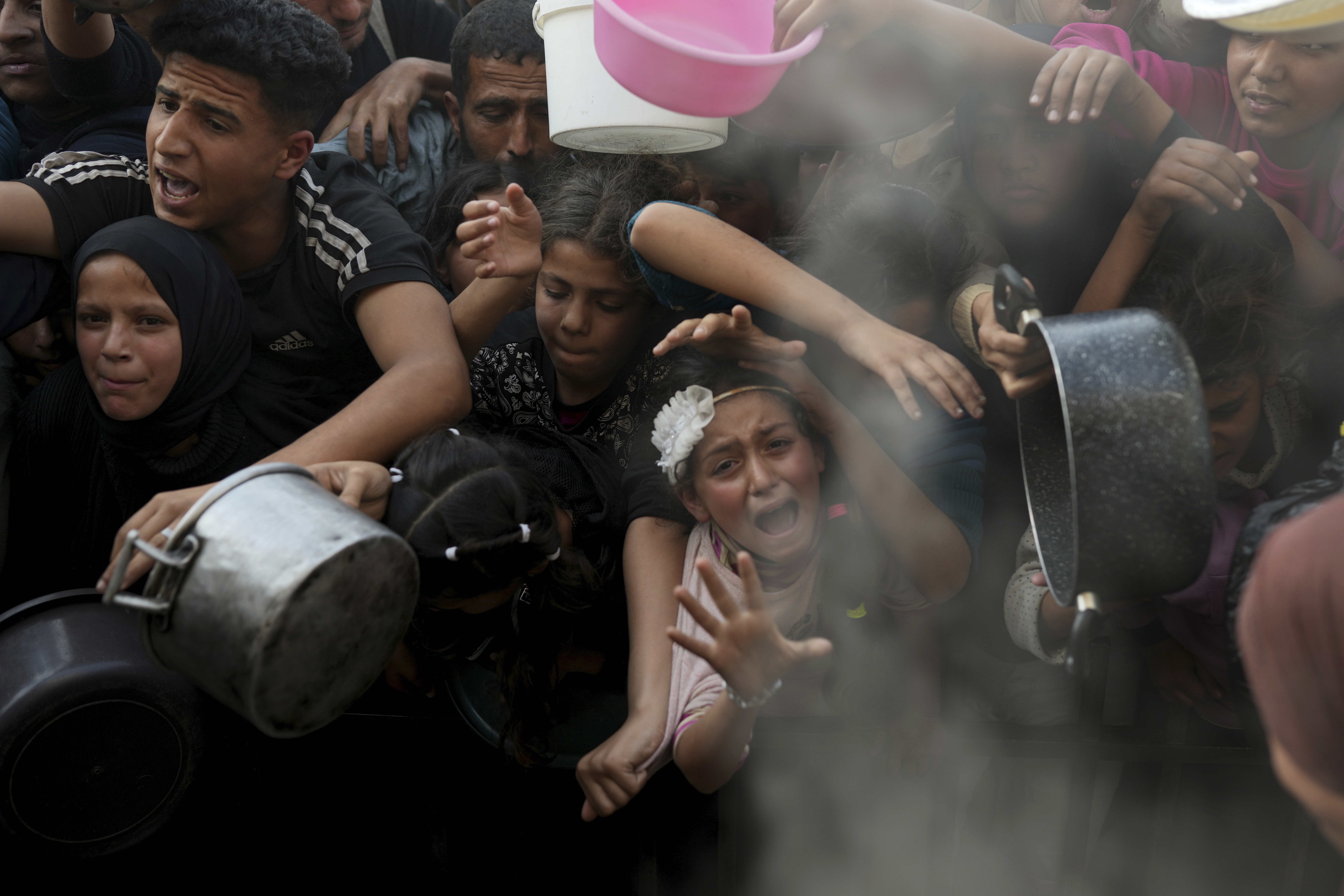 A Palestinian girl struggles as she and others try to get donated food at a distribution center in Beit Lahiya, northern Gaza Strip, Sunday, March 16, 2025. (AP Photo/Abdel Kareem Hana)