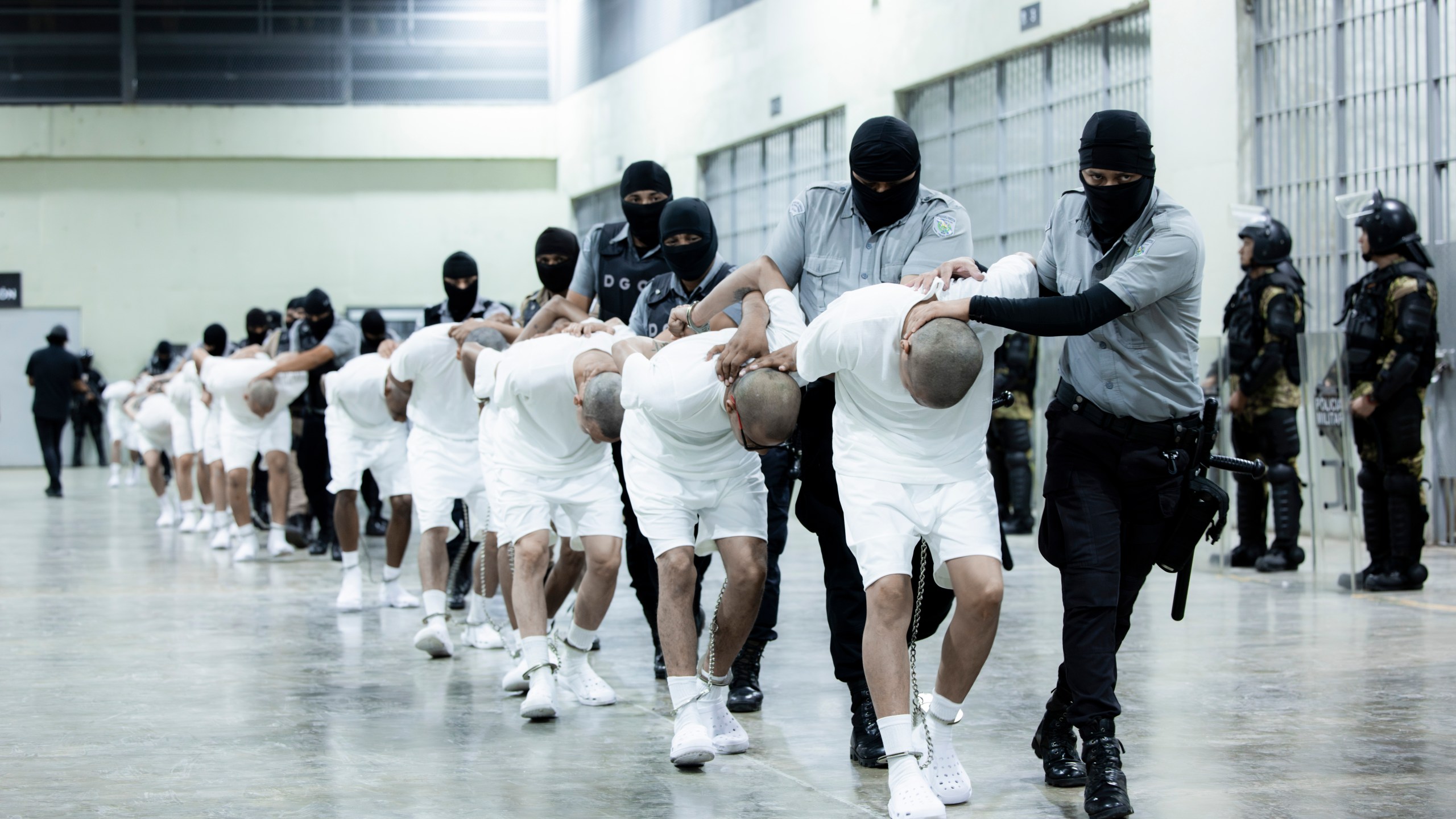 In this photo provided by El Salvador's presidential press office, prison guards transfer deportees from the U.S., alleged to be Venezuelan gang members, to the Terrorism Confinement Center in Tecoluca, El Salvador, Sunday, March 16, 2025. (El Salvador presidential press office via AP)