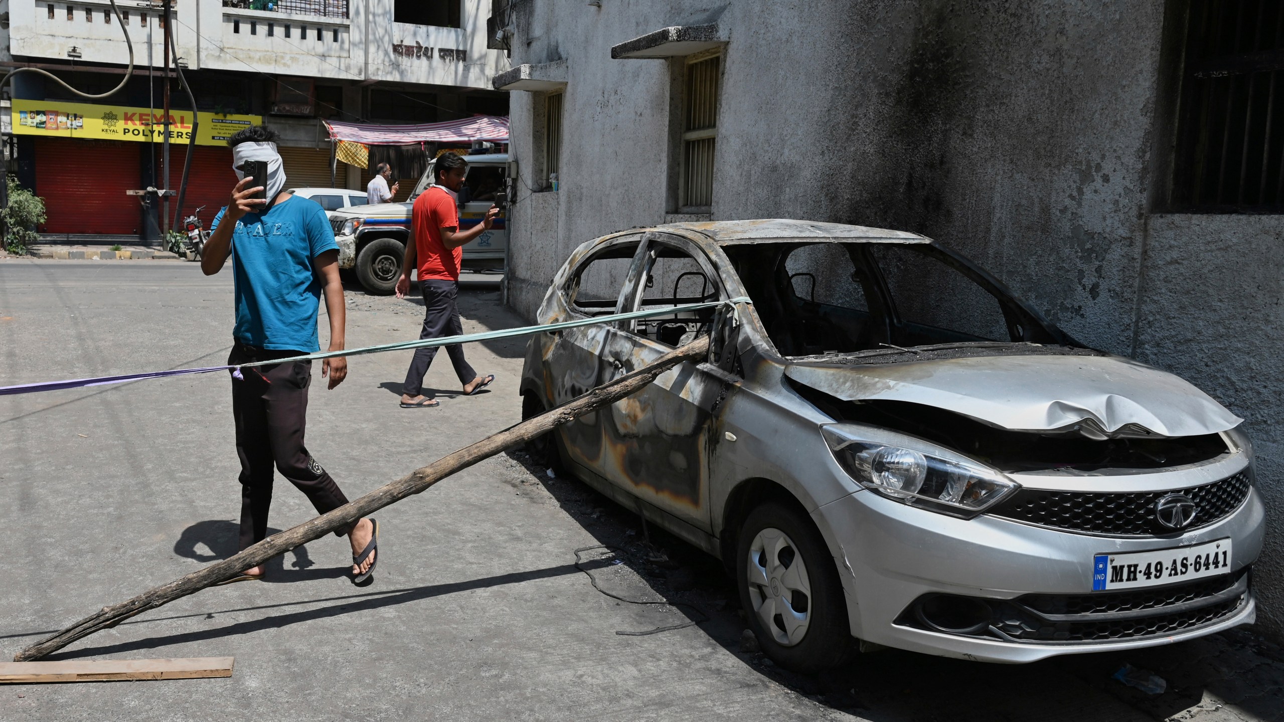 Passerby take photos of a burnt vehicle a day after communal clashes sparked by protests demanding removal of the tomb of 17th-century Muslim Mughal ruler Aurangzeb in Nagpur, India, Tuesday, March 18, 2025. (AP Photo)