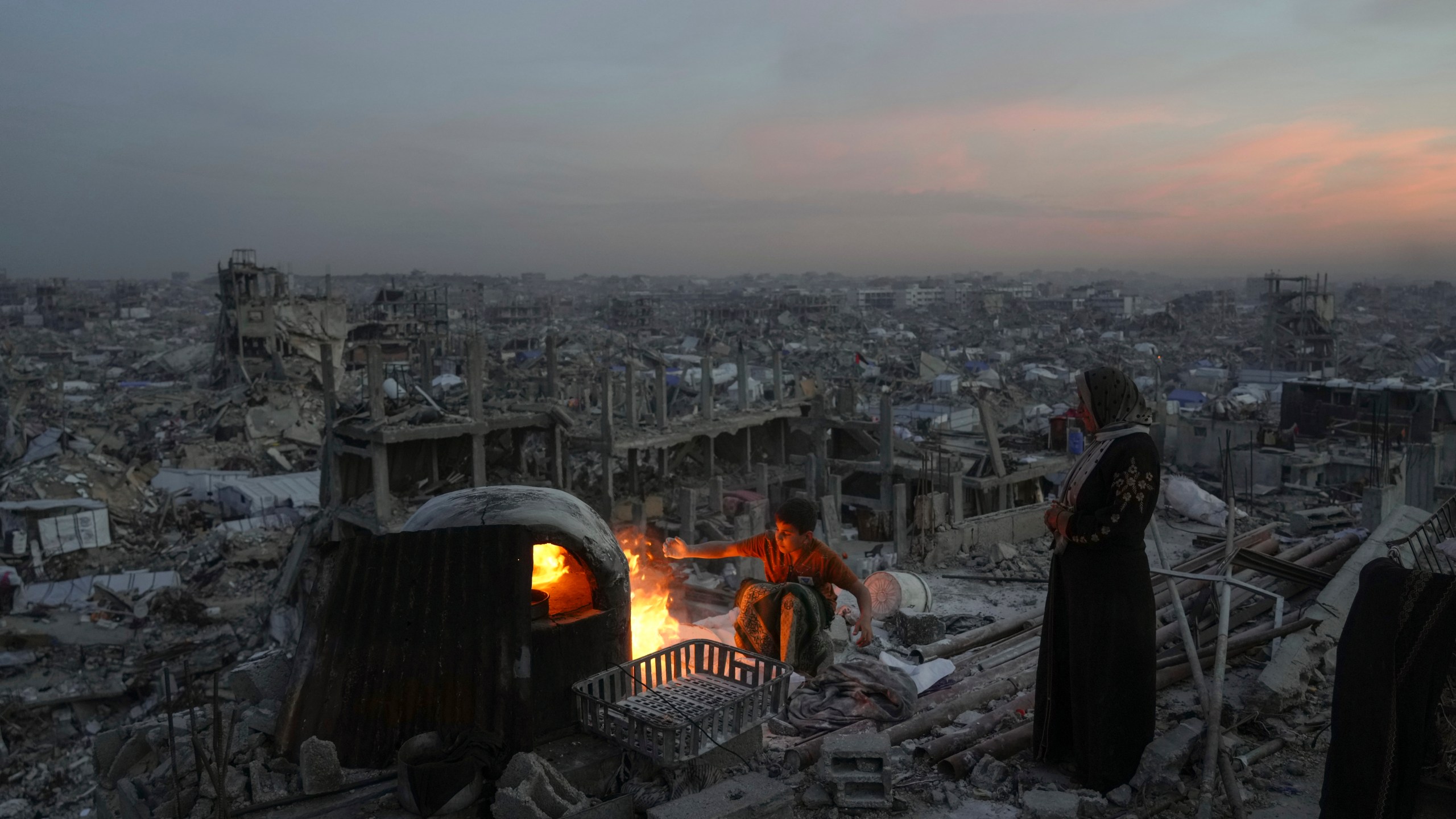 Palestinians Ali Marouf and his mother Aisha cook on fire on the roof of their destroyed house by the Israeli army's air and ground offensive in Jabaliya, Gaza Strip, on Monday, March 17, 2025. (AP Photo/Jehad Alshrafi)