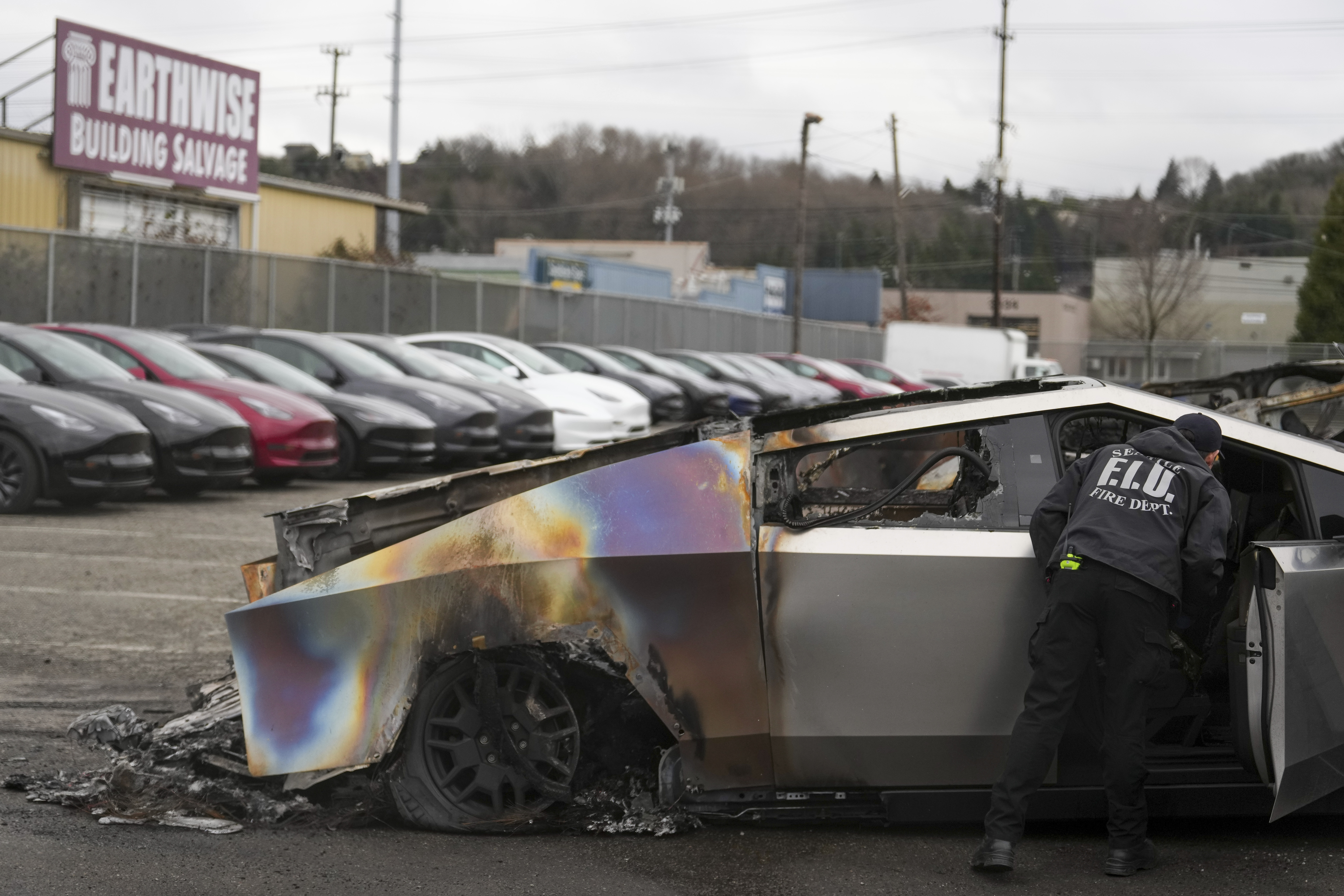 FILE - A member of the Seattle Fire Department inspects a burned Tesla Cybertruck at a Tesla lot in Seattle, Monday, March 10, 2025. (AP Photo/Lindsey Wasson, File)