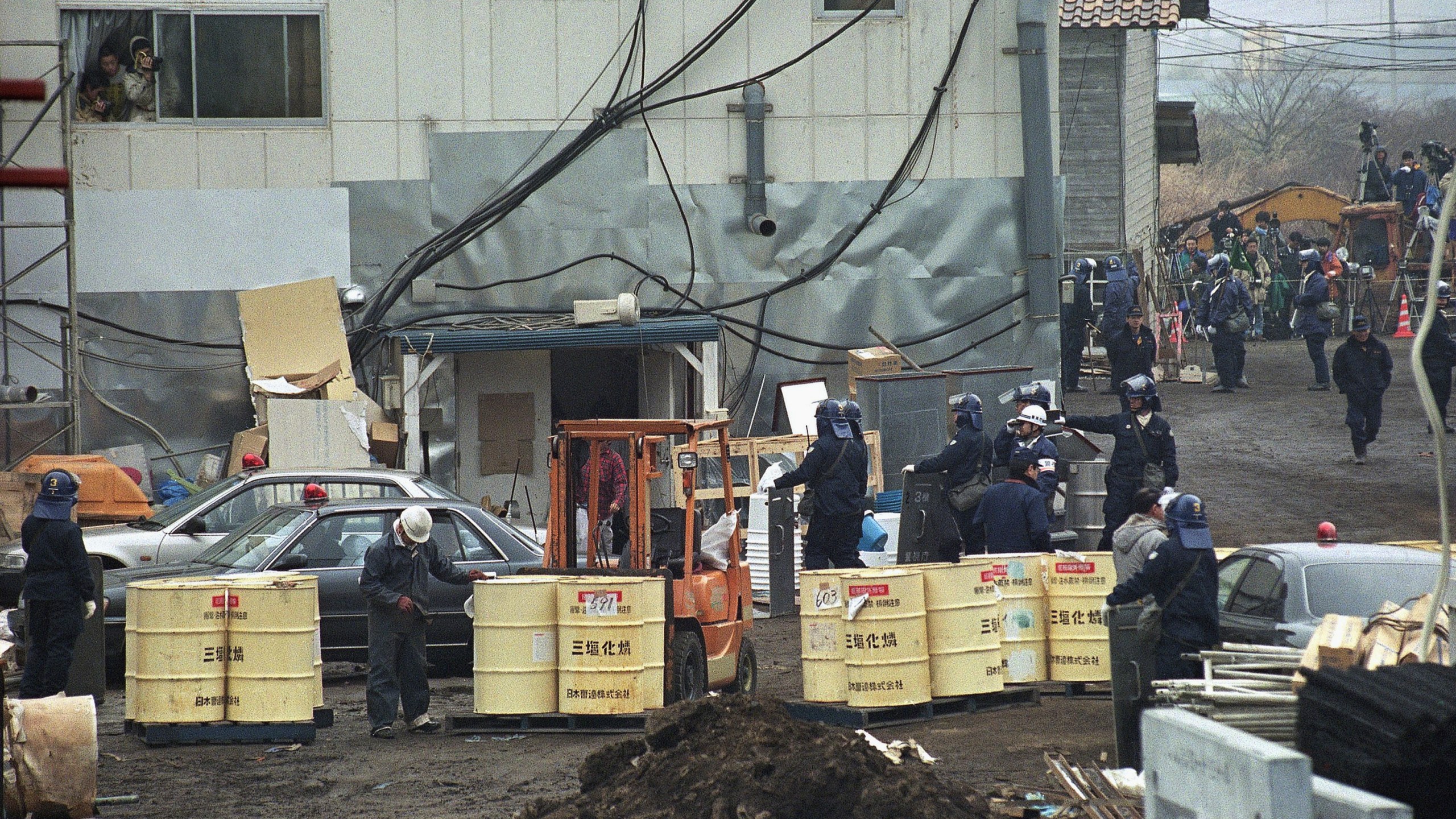 FILE - Aum Shinrikyo members look out from a window to observe the fourth-day of a police raid operation at No. 6 Satian, one of the doomsday cult's communes near Mount Fuji in Kamikuishiki, west of Tokyo, March 25, 1995. (AP Photo/Hiroshi Otabe, File)