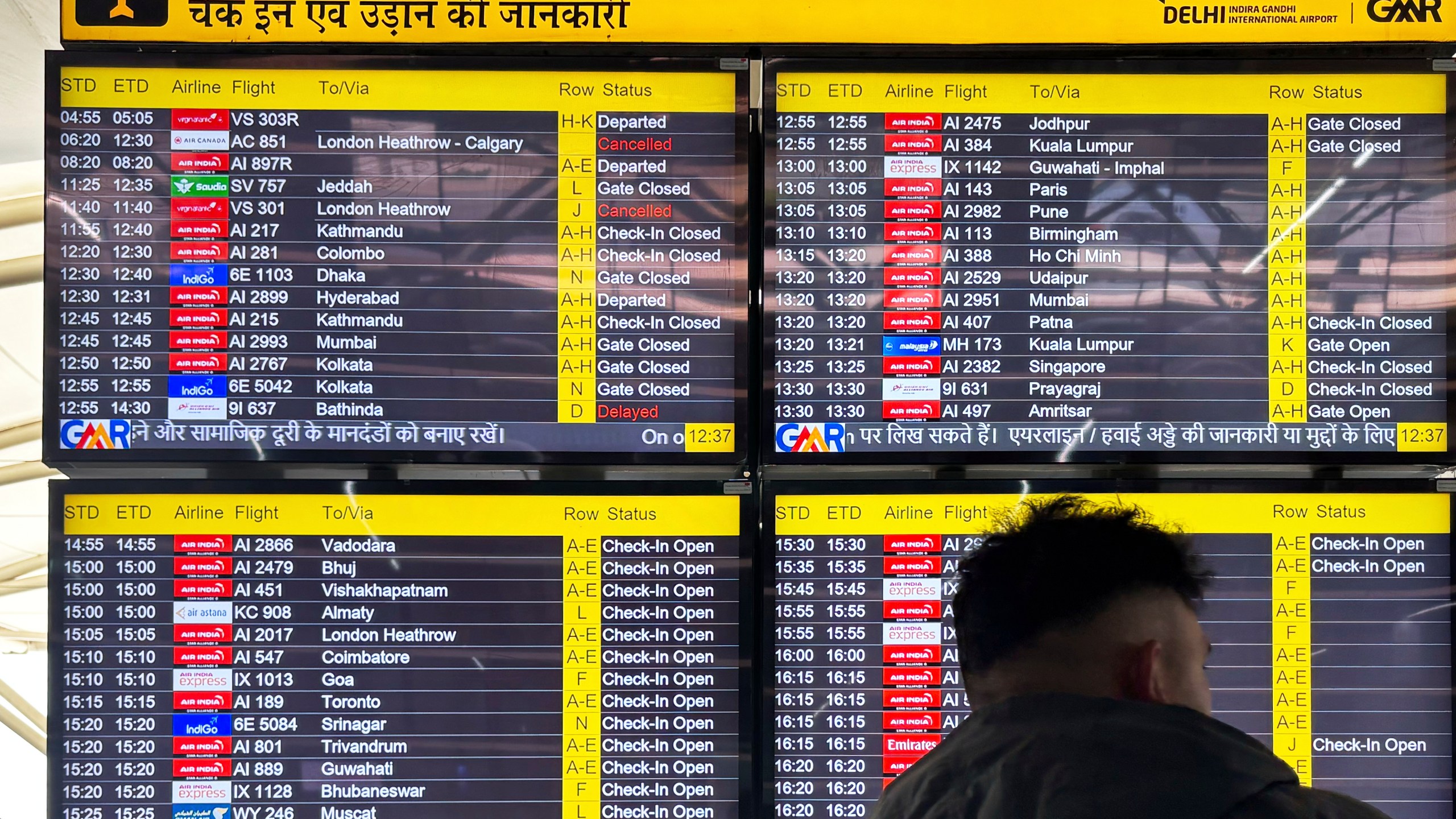 A passenger stands in front of a flight information screen showing cancelled flights destined for the Heathrow Airport in London, at the Indira Gandhi International Airport, in New Delhi, India, Friday, March 21, 2025. (AP Photo/Shonal Ganguly)