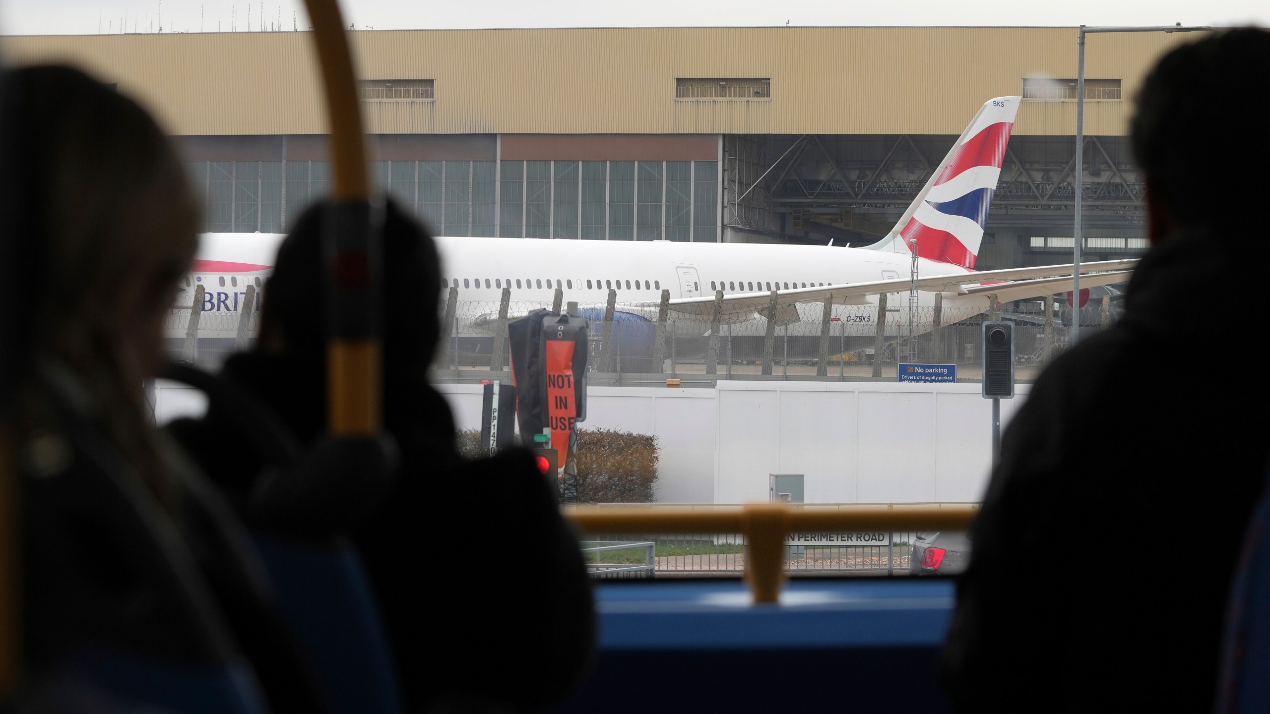 Passengers on a bus look at a parked plane as Britain's Heathrow Airport has closed for the full day Friday after an electrical substation fire knocked out its power, disrupting flights for hundreds of thousands of passengers at one of Europe's biggest travel hubs in London, Friday, March 21, 2025.(AP Photo/Kin Cheung)