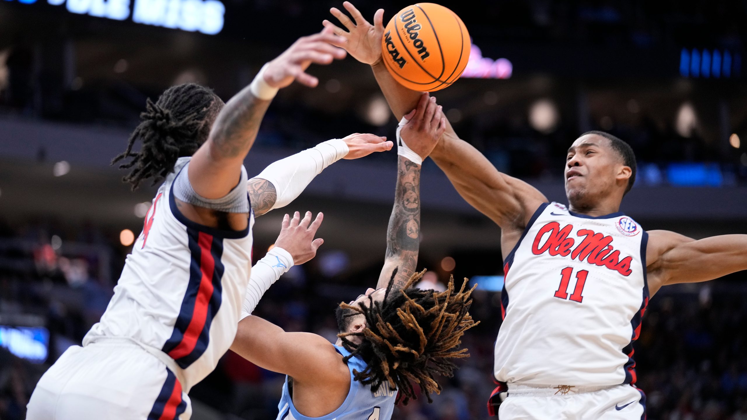 Mississippi guard Matthew Murrell (11) blocks a shot by North Carolina guard RJ Davis (4) as Mississippi guard Dre Davis, left, also reaches for the ball during the second half in the first round of the NCAA college basketball tournament, Friday, March 21, 2025, in Milwaukee. (AP Photo/Kayla Wolf)