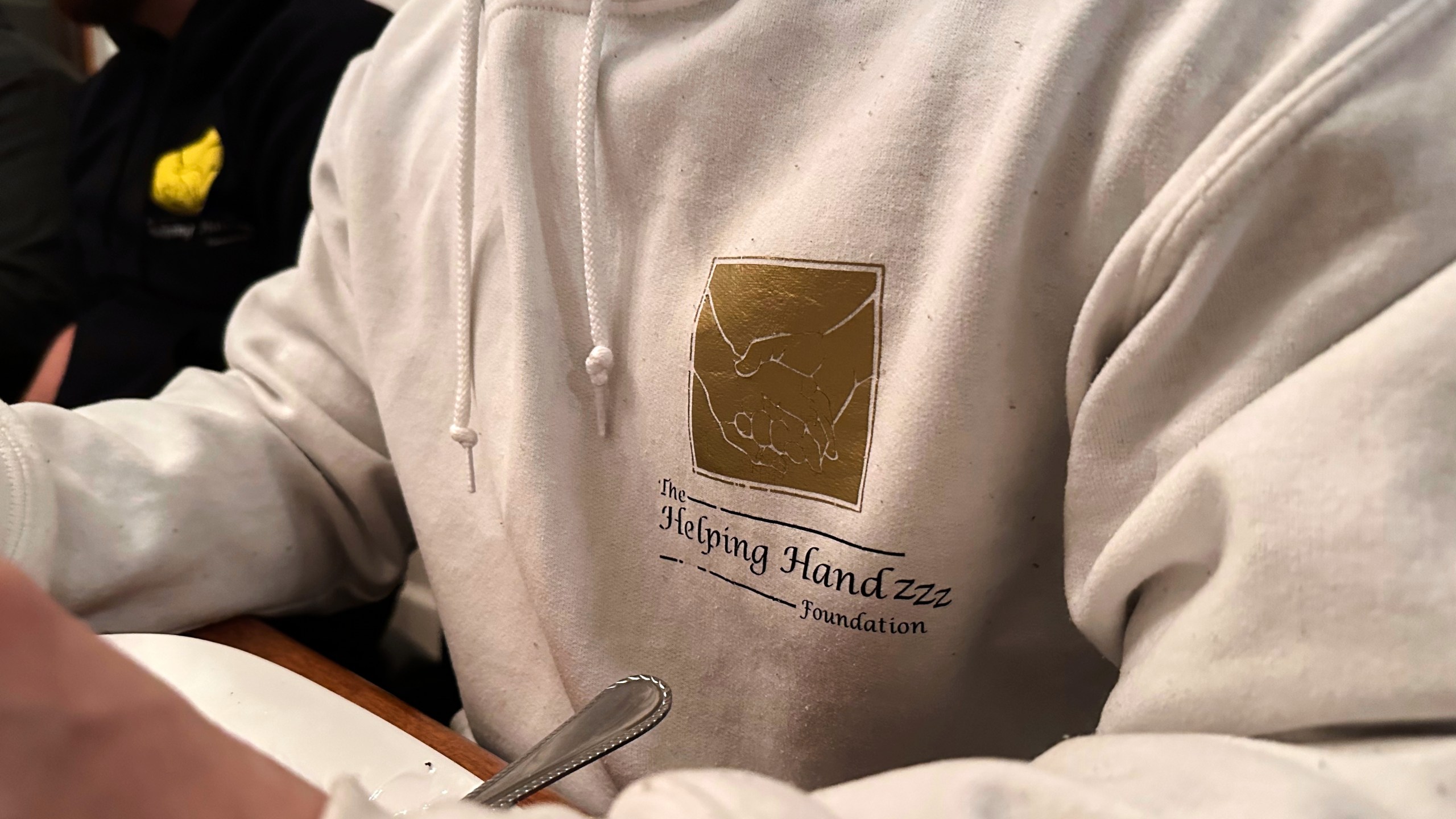 The Helping Handzzz Foundation board member Daoud Wehbi wears a branded sweatshirt during an iftar dinner Friday, March 7, 2025, in Dearborn, Mich. (AP Photo/Mike Householder)