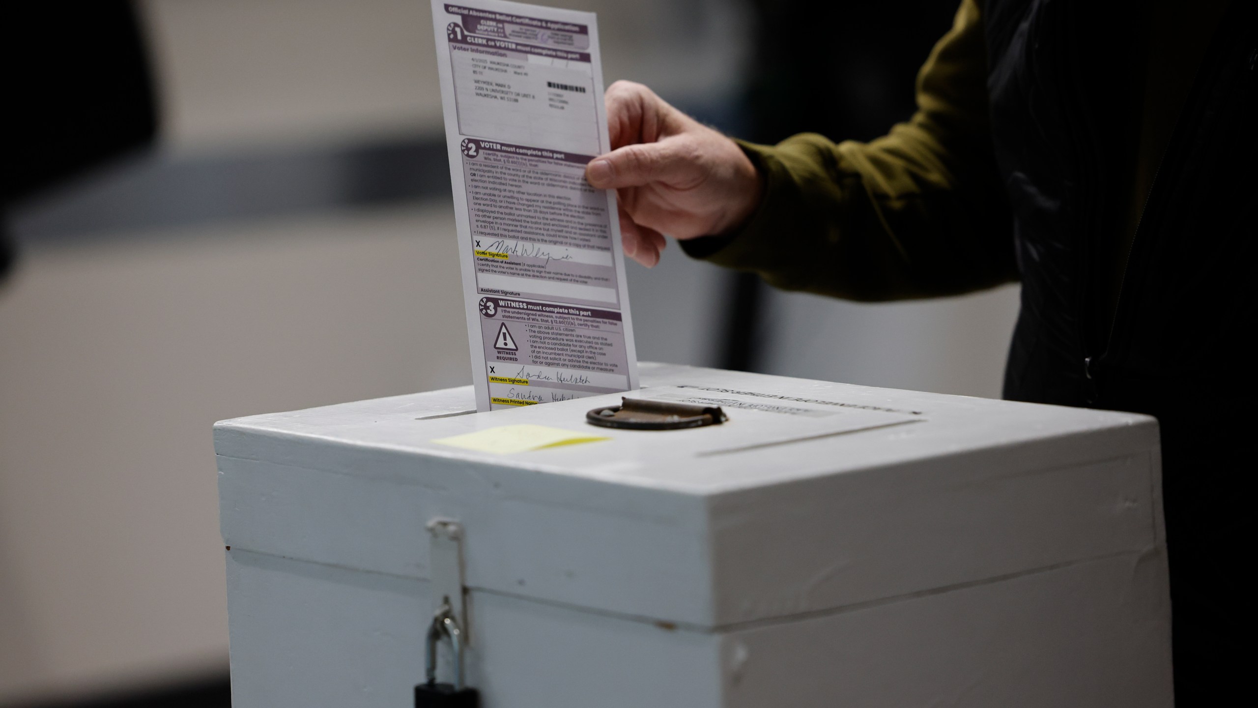 A man places his ballot in a box during early voting in Waukesha, Wis Tuesday, March 18, 2025. (AP Photo/Jeffrey Phelps)