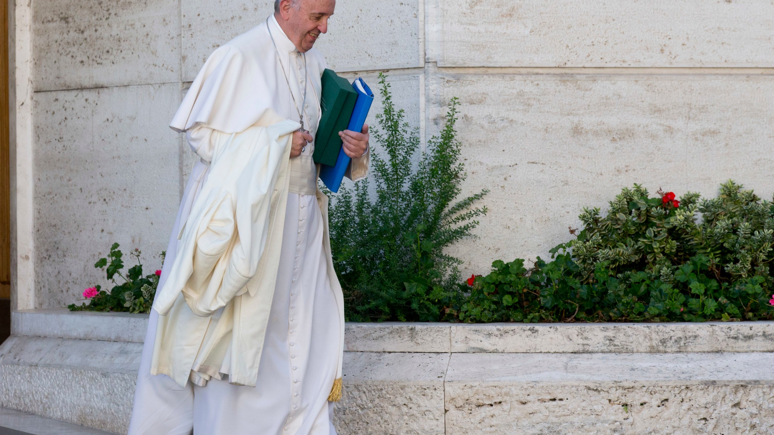 FILE - In this Oct. 24, 2015 file photo, Pope Francis carries his coat and documents as he leaves after a morning session of the last day of the Synod of bishops, at the Vatican. (AP Photo/Alessandra Tarantino, file)