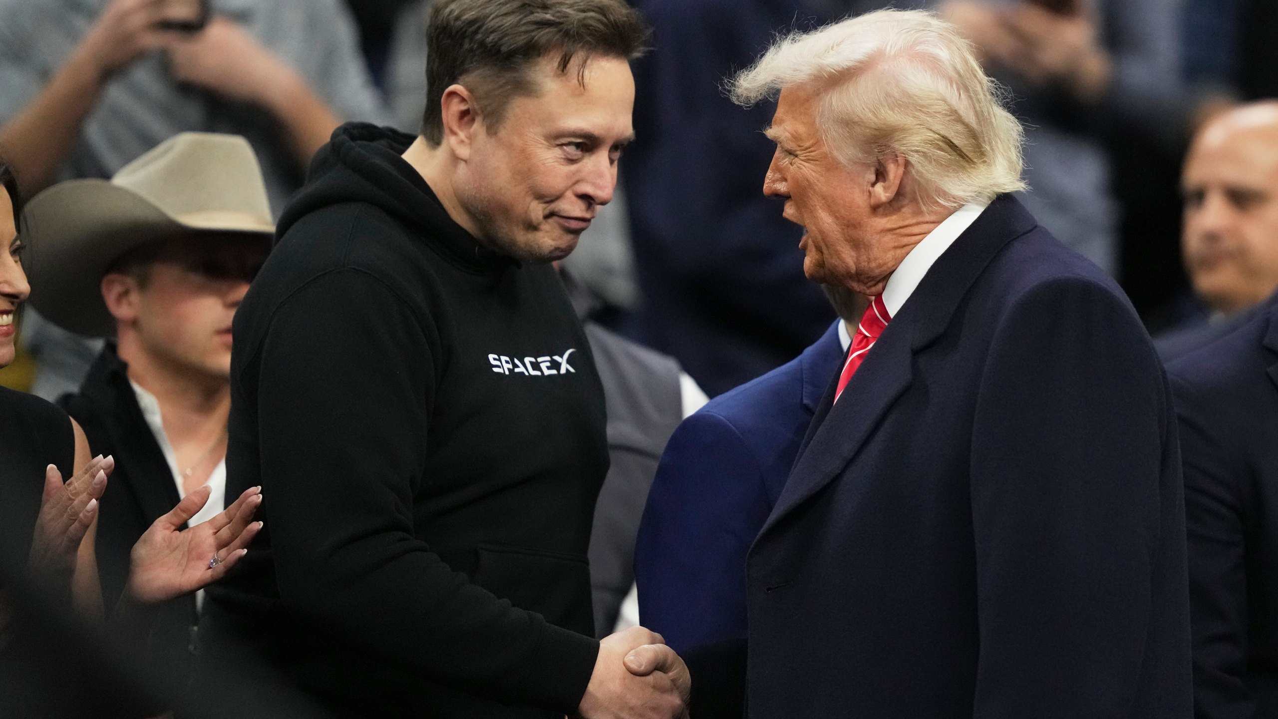 Elon Musk, left, shakes hands with President Donald Trump at the finals for the NCAA wrestling championship, Saturday, March 22, 2025, in Philadelphia. (AP Photo/Matt Rourke)