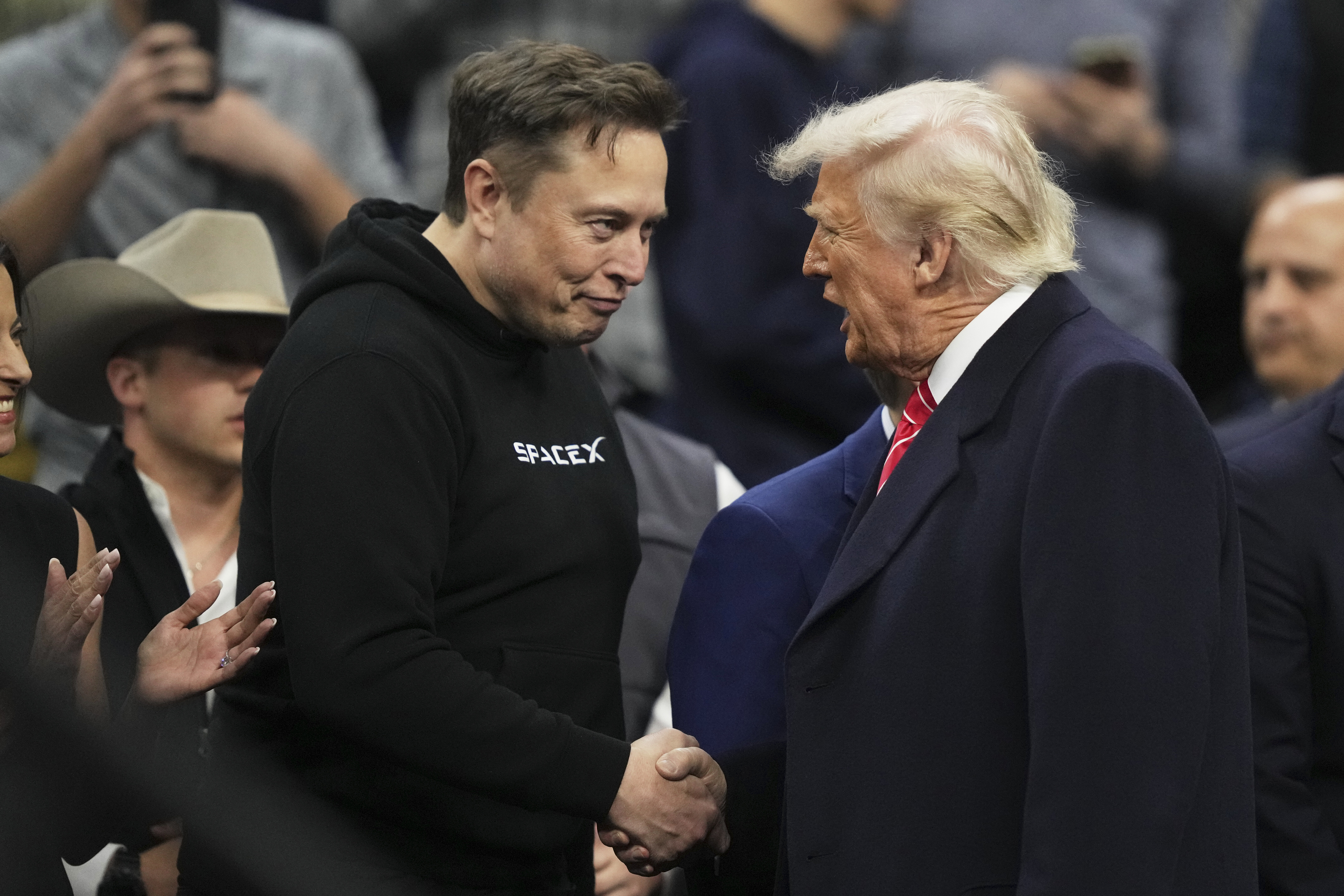 Elon Musk, left, shakes hands with President Donald Trump at the finals for the NCAA wrestling championship, Saturday, March 22, 2025, in Philadelphia. (AP Photo/Matt Rourke)