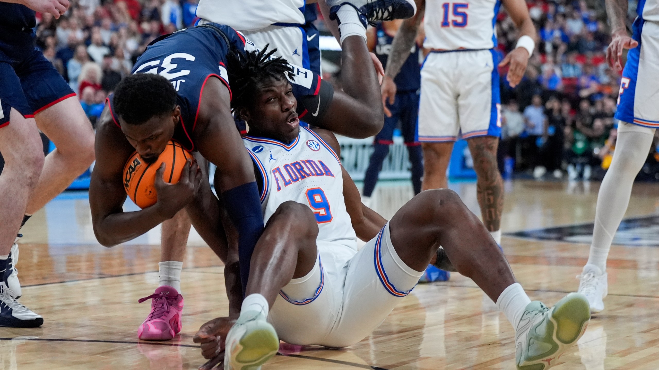 UConn center Samson Johnson falls over Florida center Rueben Chinyelu during the first half in the second round of the NCAA college basketball tournament, Sunday, March 23, 2025, in Raleigh, N.C. (AP Photo/Chris Carlson)