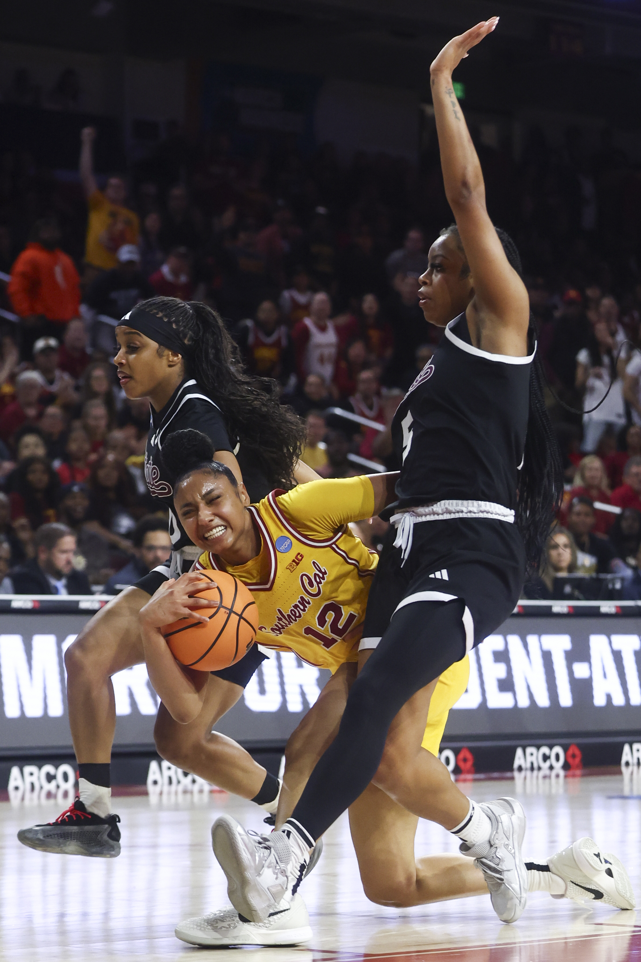 Southern California guard JuJu Watkins (12) draws a foul against Mississippi State guard Eniya Russell, left, and guard Chandler Prater (5) during the first half in the second round of the NCAA college basketball tournament Monday, March 24, 2025, in Los Angeles. (AP Photo/Jessie Alcheh)